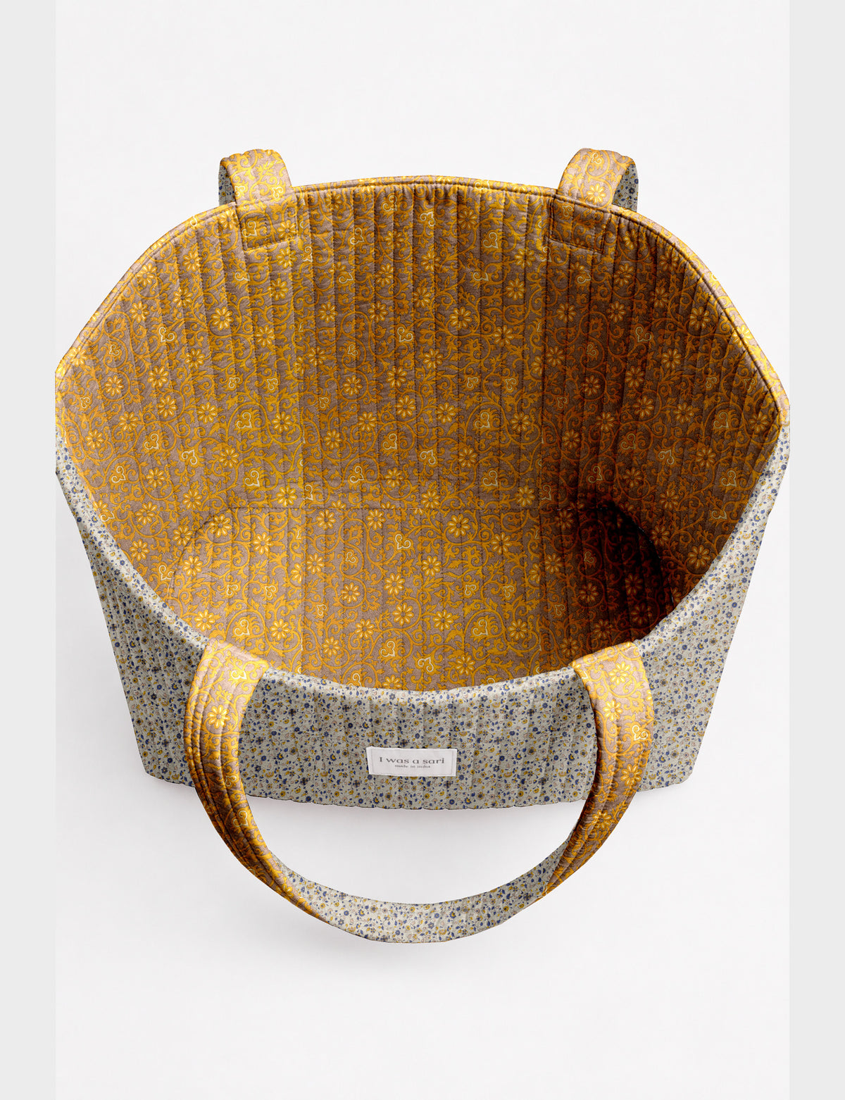 Quilted beach bag with yellow tropical exterior and red patterned interior, shown from top view with handles visible
