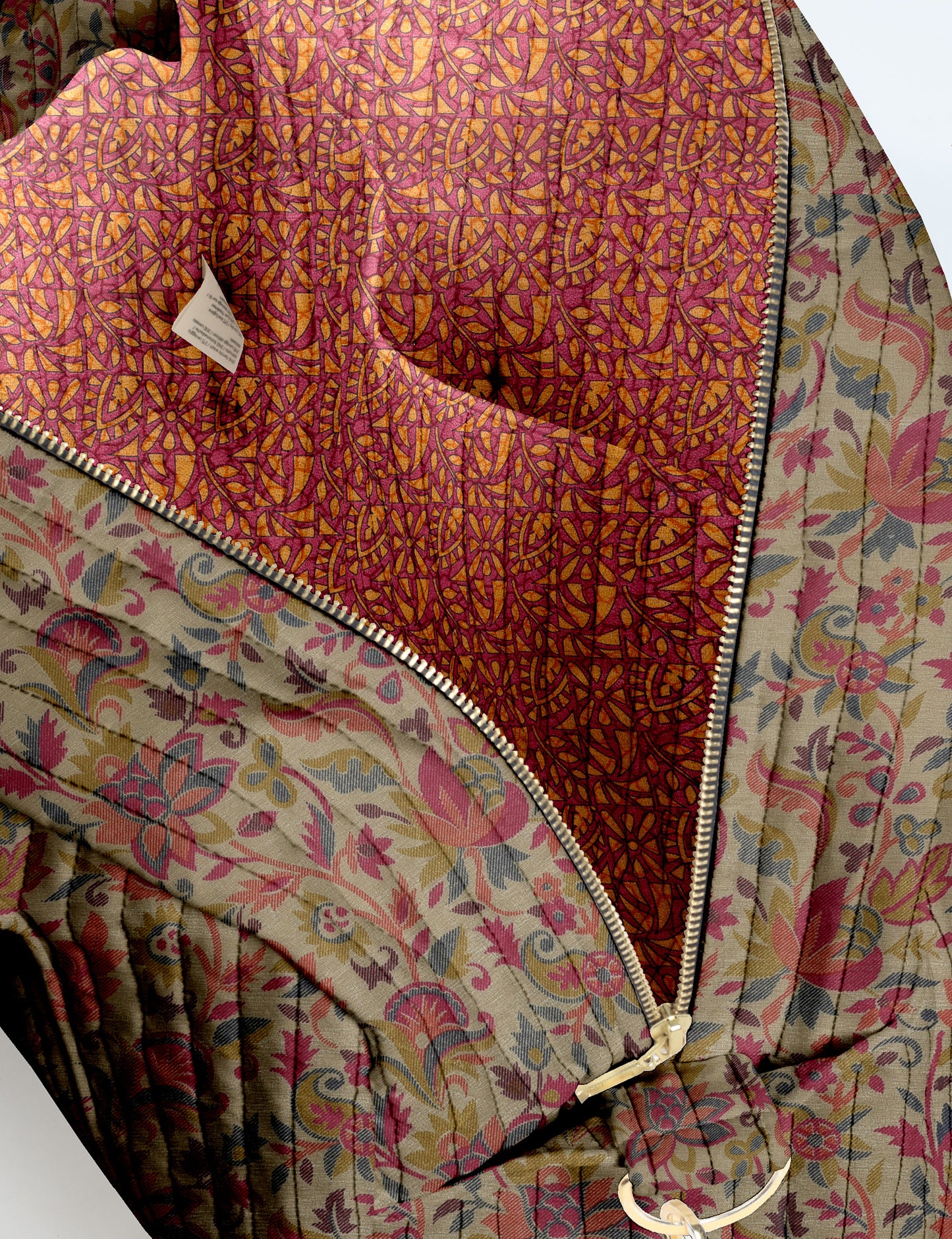 Brown quilted duffle bag with paisley pattern, front zip pocket, dual handles, and label reading "I was a sari"