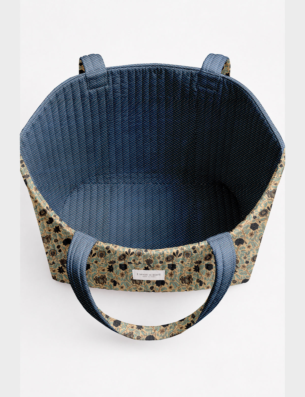 Quilted beach bag with yellow tropical exterior and red patterned interior, shown from top view with handles visible