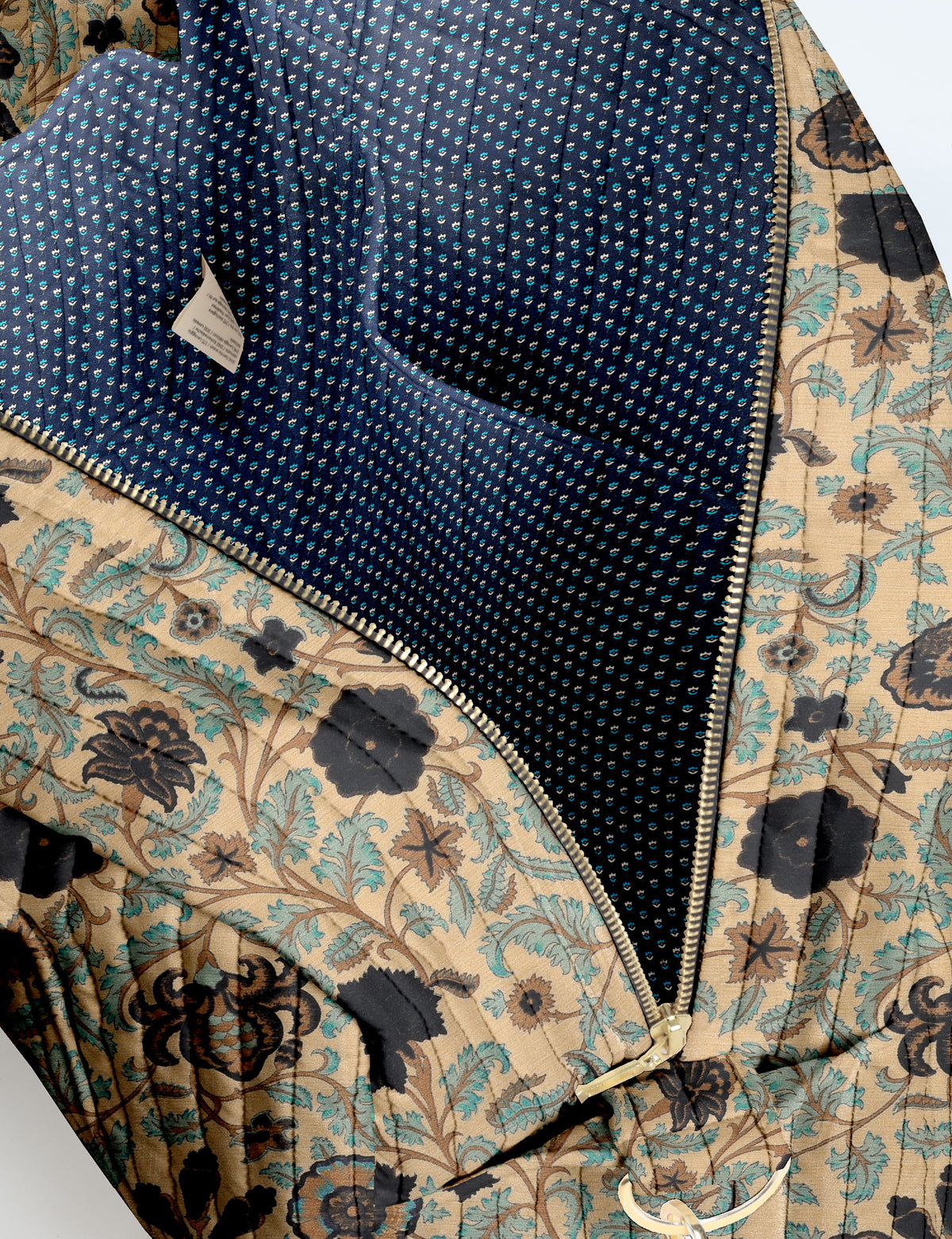 Brown quilted duffle bag with paisley pattern, front zip pocket, dual handles, and label reading "I was a sari"