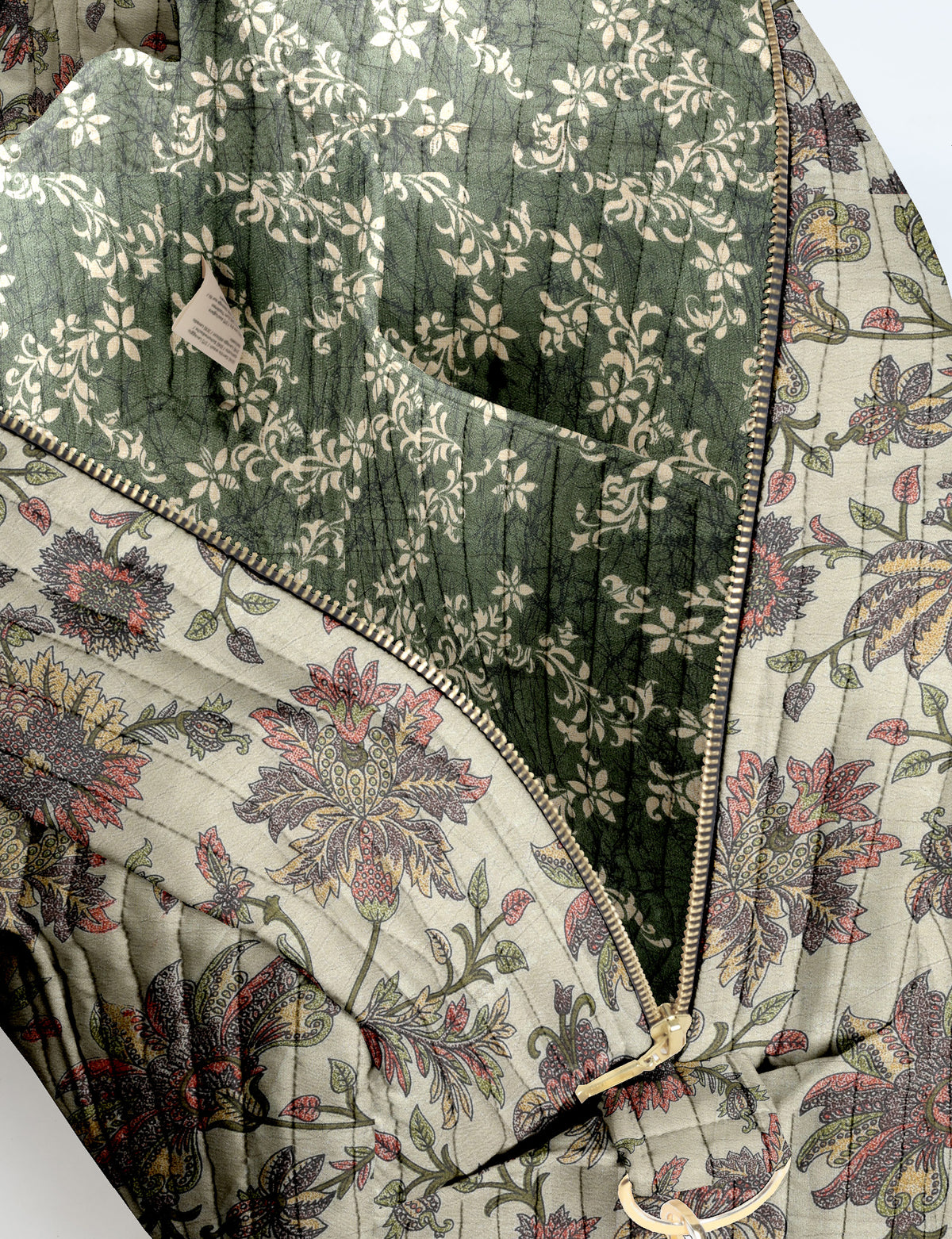 Brown quilted duffle bag with paisley pattern, front zip pocket, dual handles, and label reading "I was a sari"