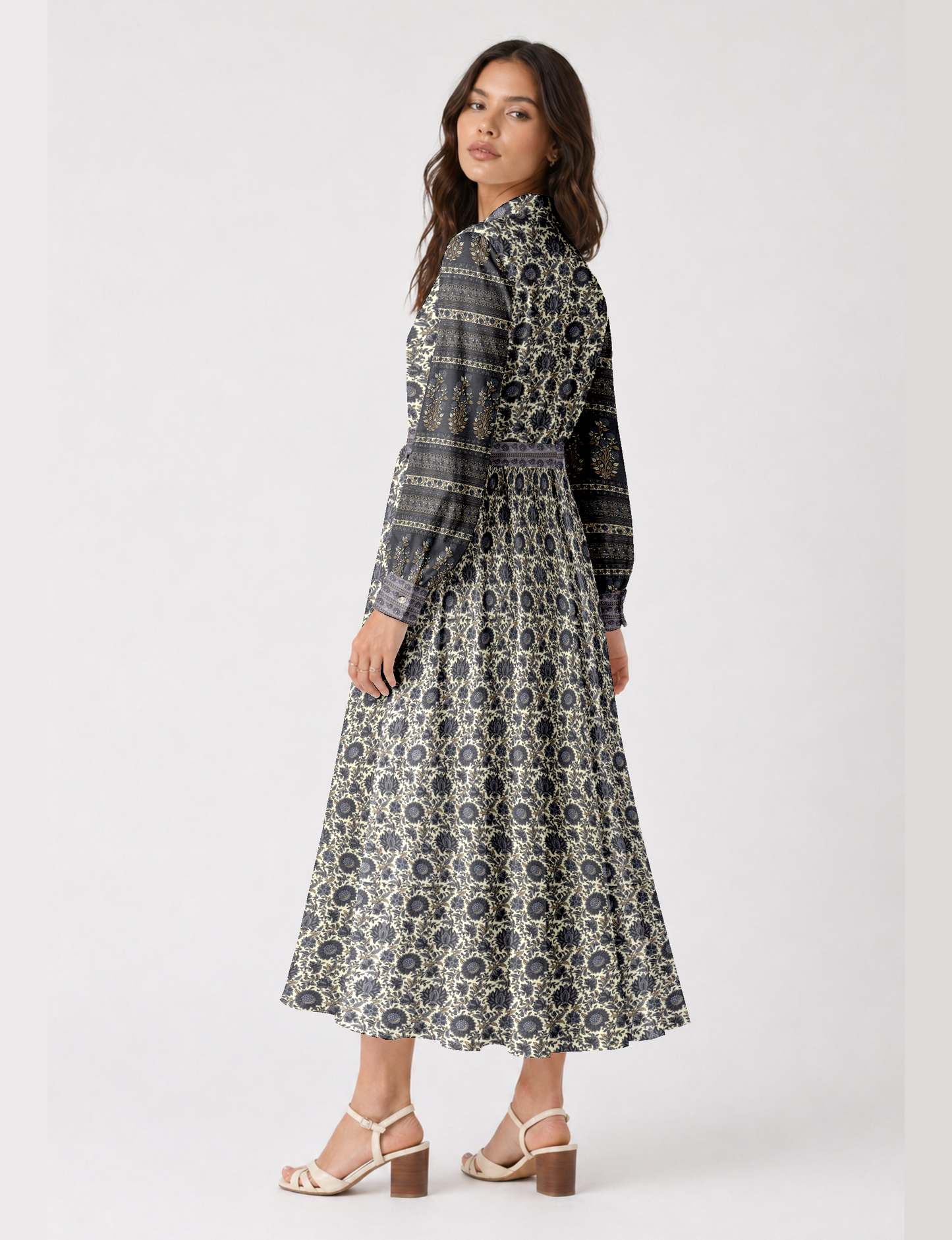 Woman wearing a long beige and black floral patterned shirt dress with long sleeves and buttoned cuffs, side view