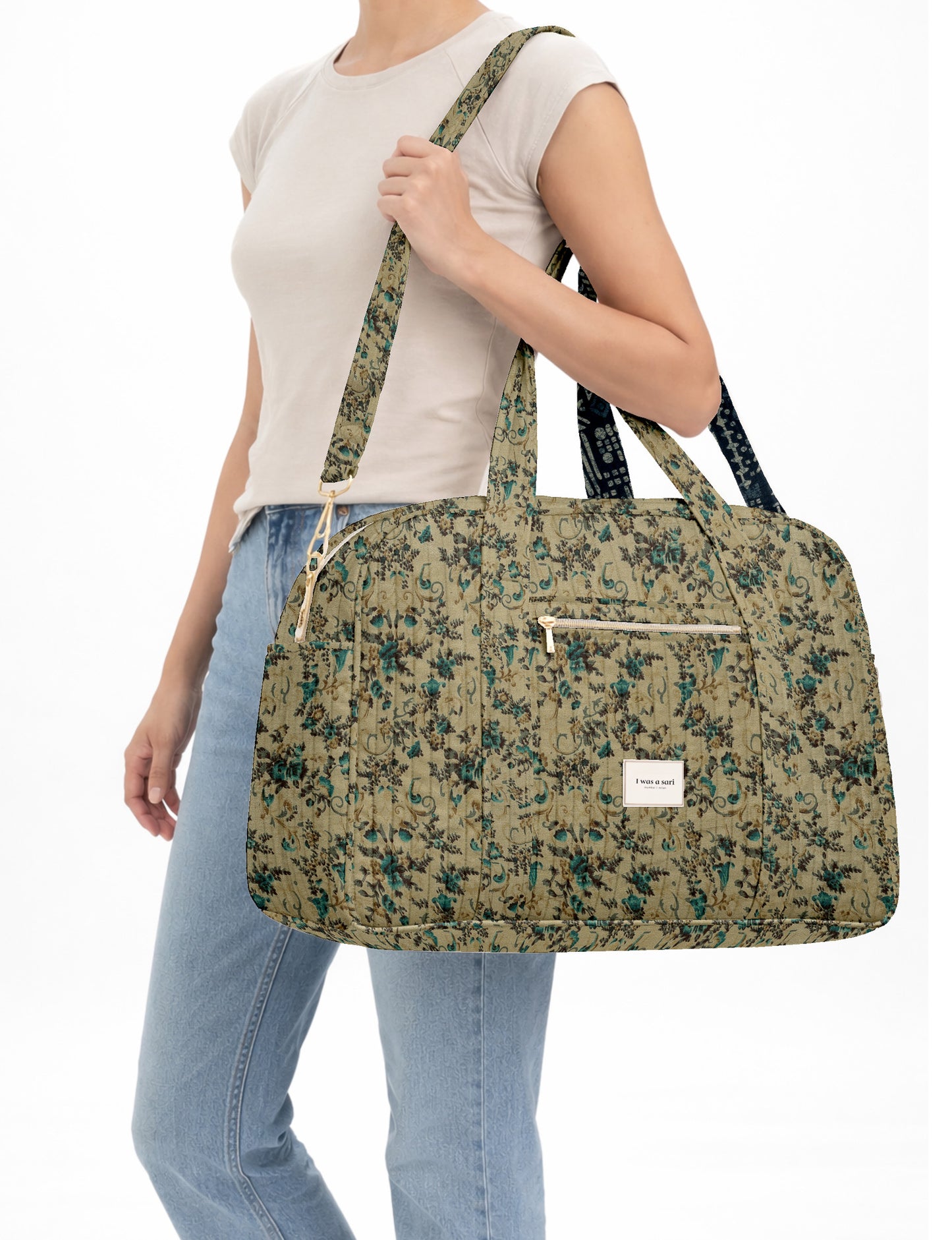 Brown quilted duffle bag with paisley pattern, front zip pocket, dual handles, and label reading "I was a sari"