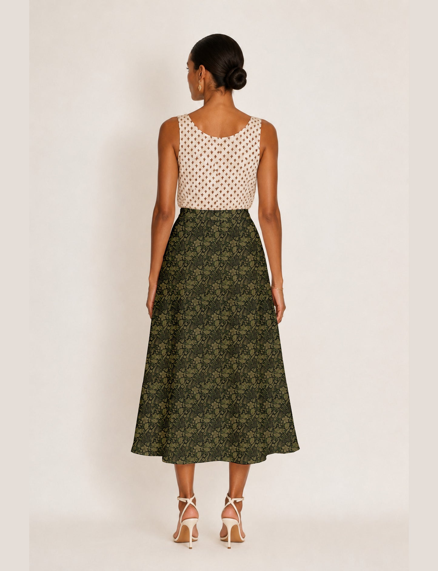 Woman wearing a yellow and black micro patterned A-line skirt with front slit, paired with beige sleeveless top and black