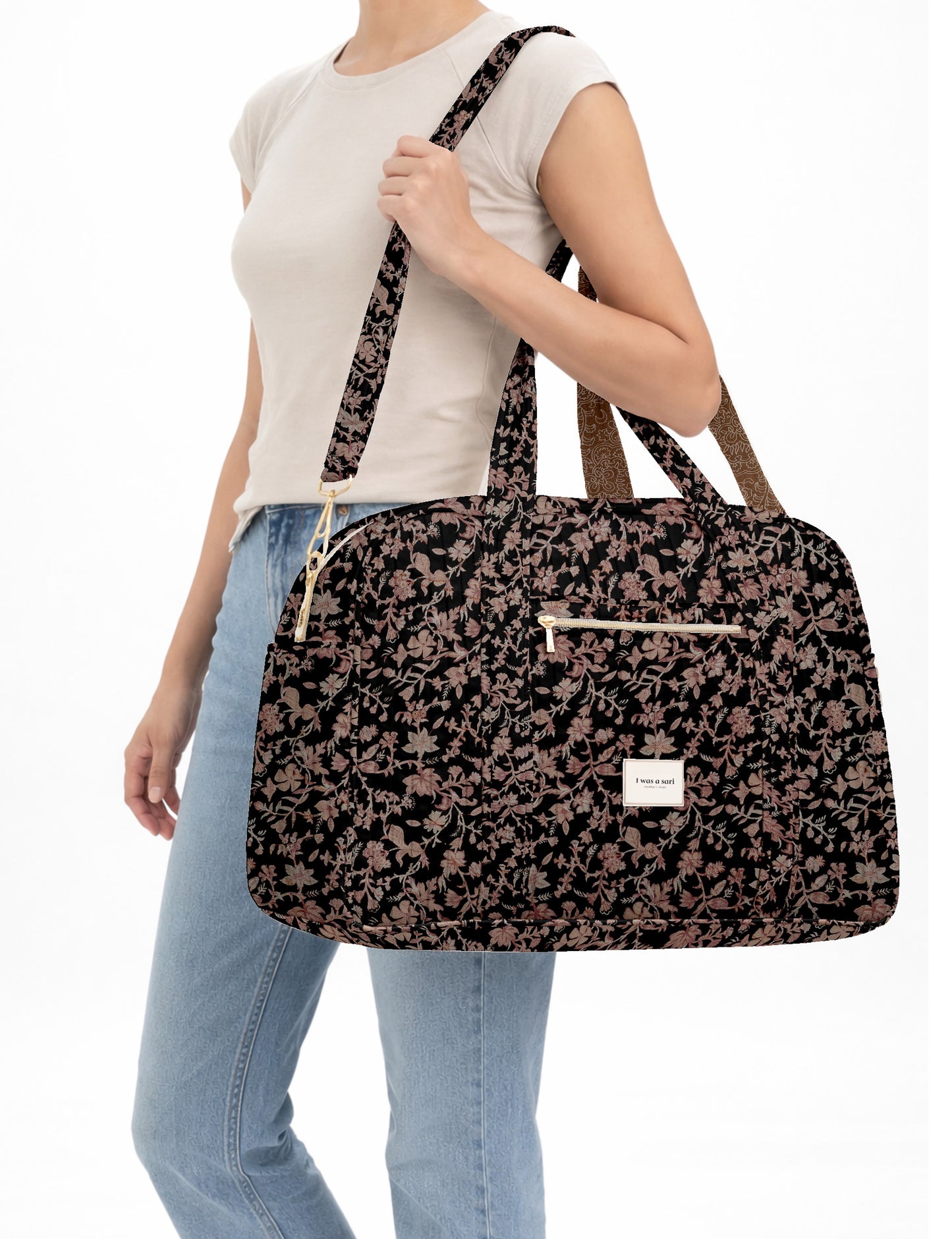 Brown quilted duffle bag with paisley pattern, front zip pocket, dual handles, and label reading "I was a sari"