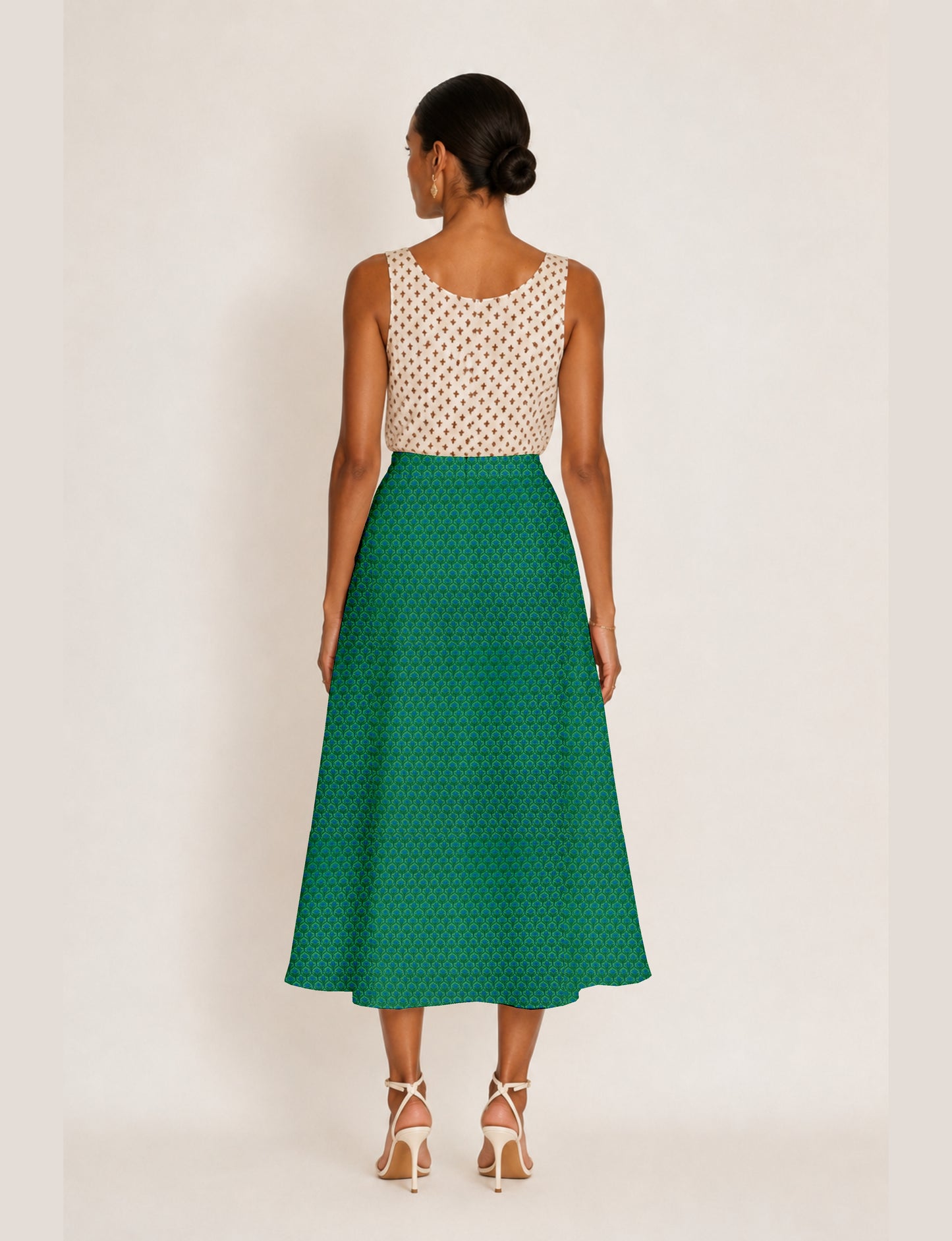 Woman wearing a yellow and black micro patterned A-line skirt with front slit, paired with beige sleeveless top and black