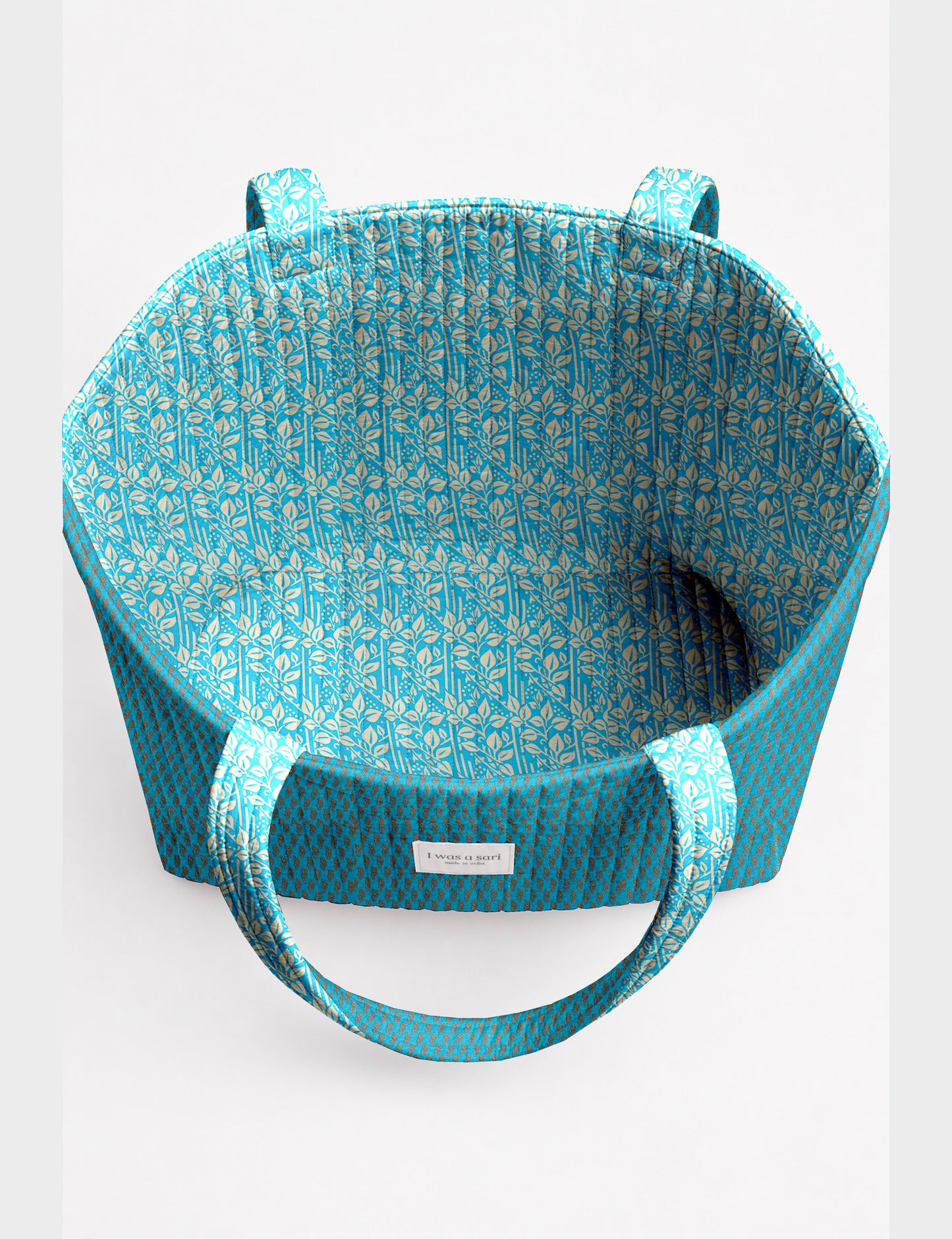 Quilted beach bag with yellow tropical exterior and red patterned interior, shown from top view with handles visible