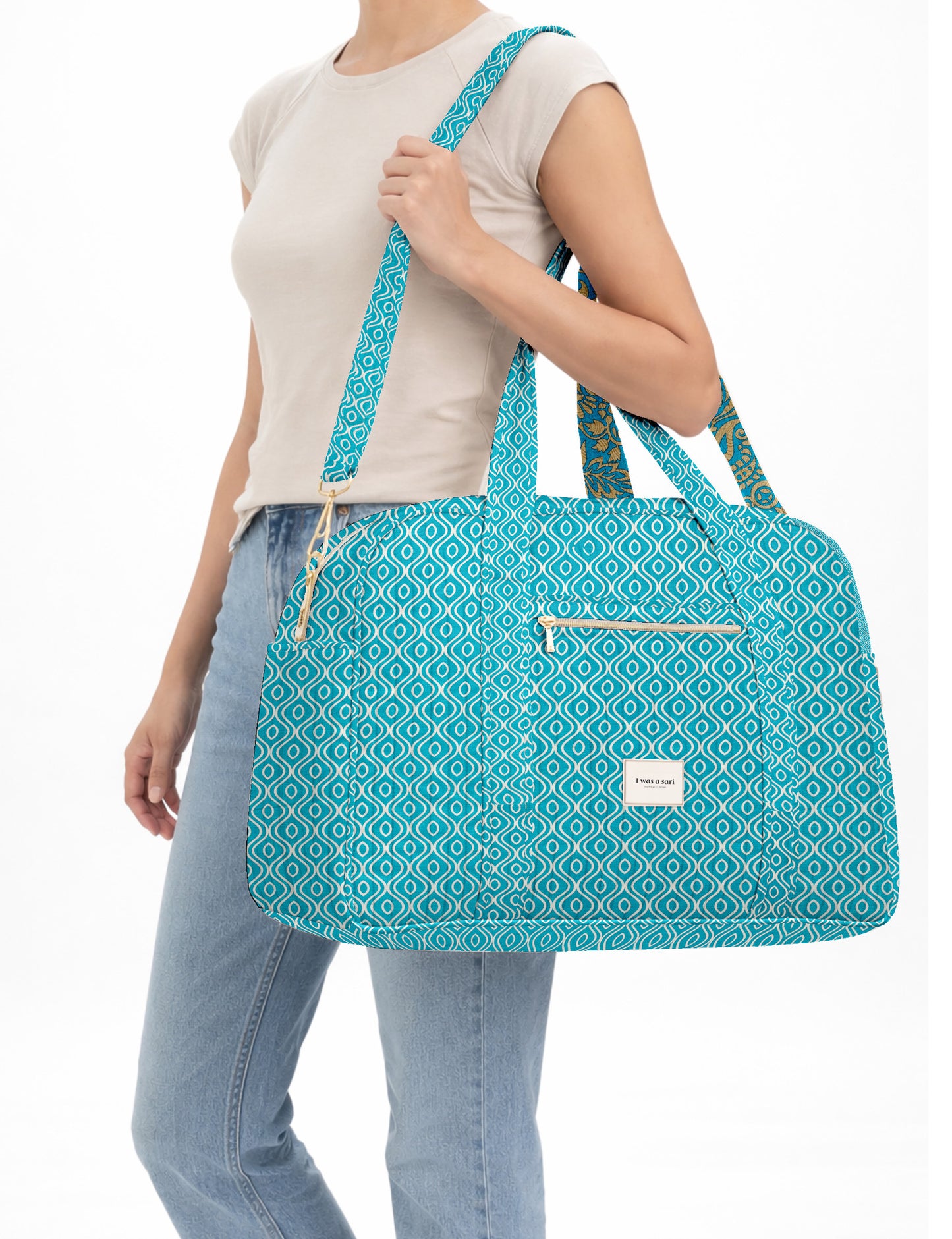 Brown quilted duffle bag with paisley pattern, front zip pocket, dual handles, and label reading "I was a sari"