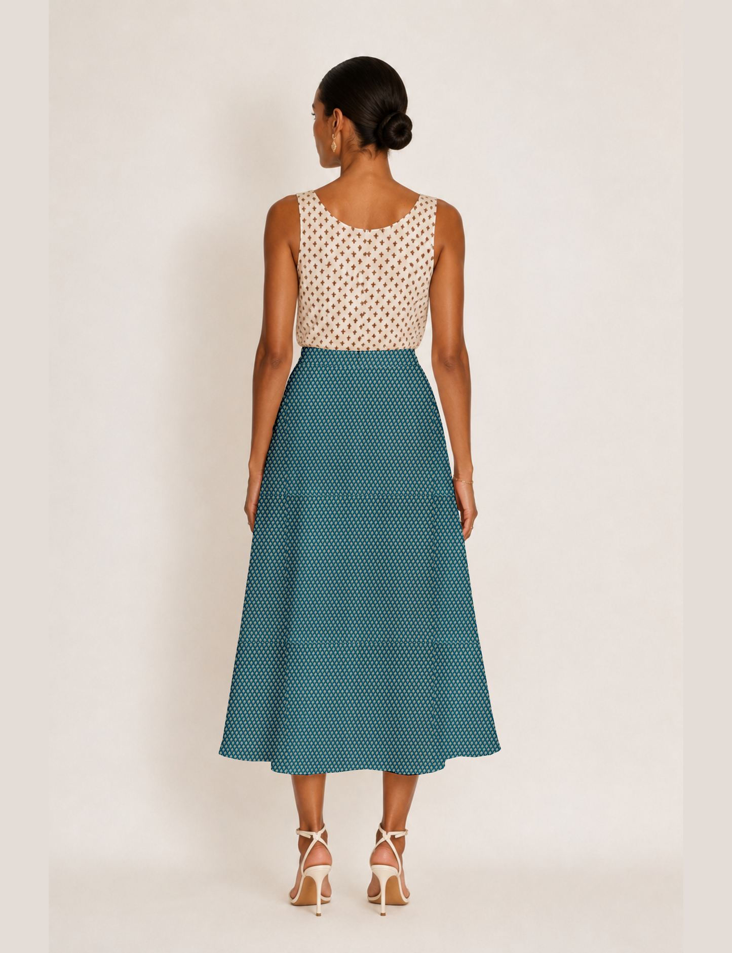 Woman wearing a yellow and black micro patterned A-line skirt with front slit, paired with beige sleeveless top and black
