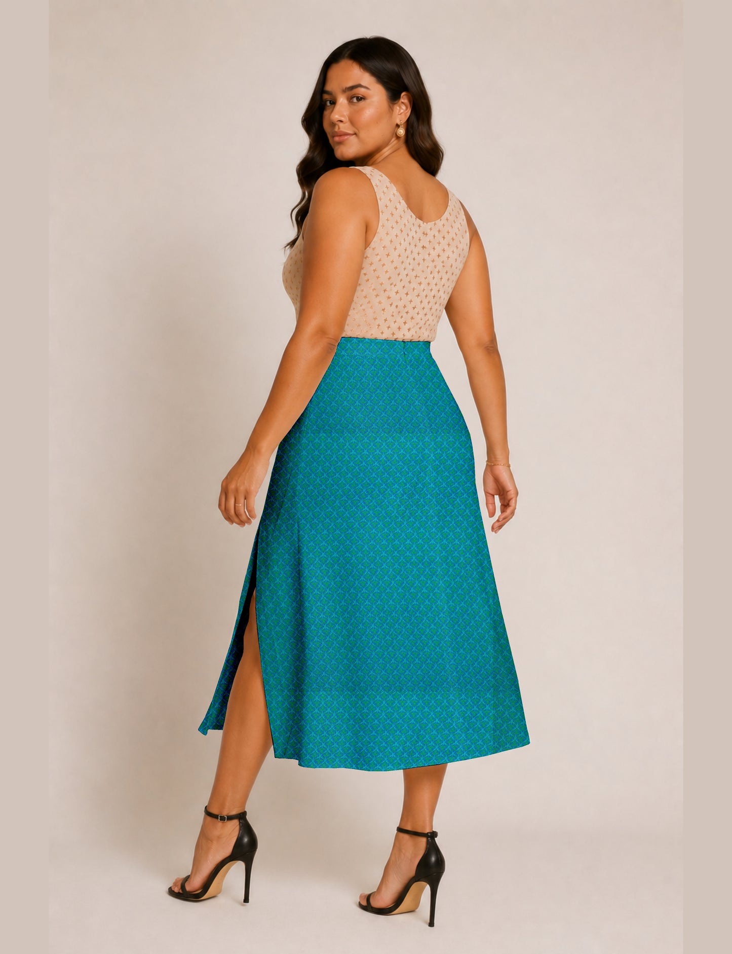Woman wearing a blue A-line skirt with micro pattern and side slit, paired with a beige sleeveless top, back view