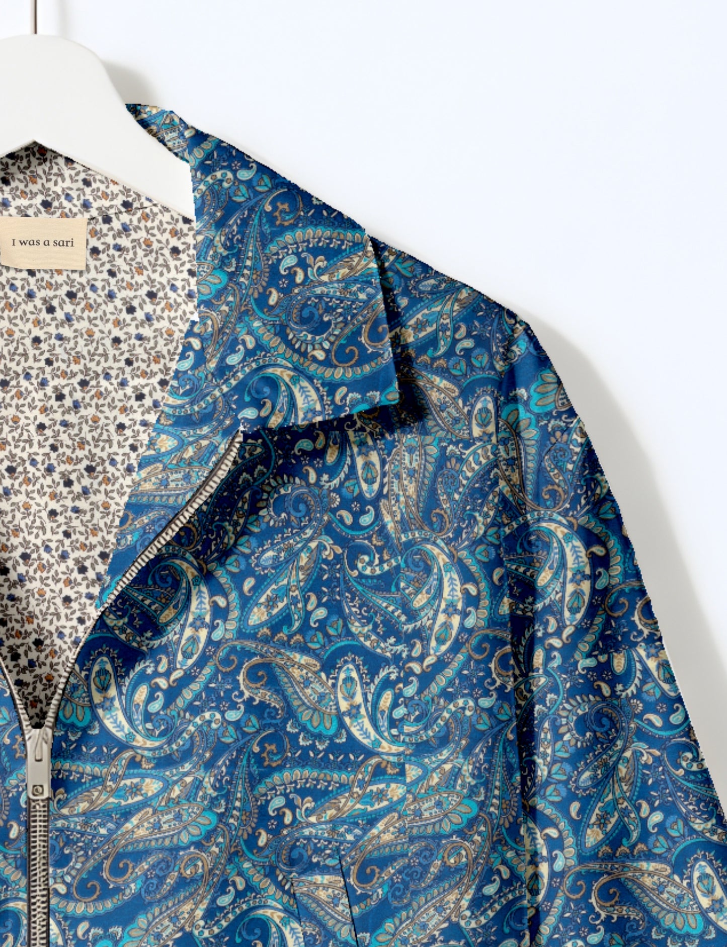 Women's cropped bomber jacket with twin metallic front zippers, welt pockets, elasticated hem and cuffs, and contrast sari print lining.