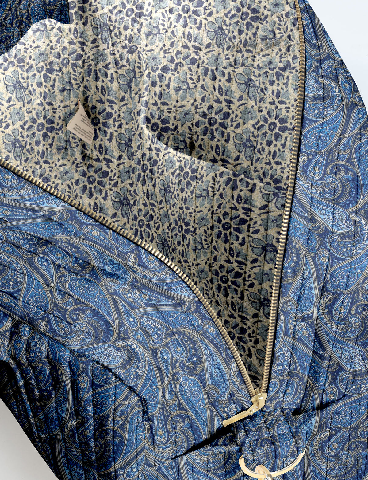 Brown quilted duffle bag with paisley pattern, front zip pocket, dual handles, and label reading "I was a sari"