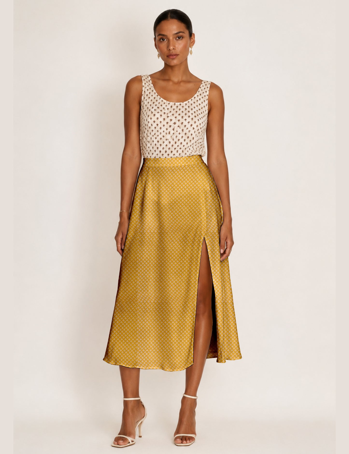 Woman wearing a yellow and navy blue A-line skirt with a slit and a sleeveless beige top with brown micro print