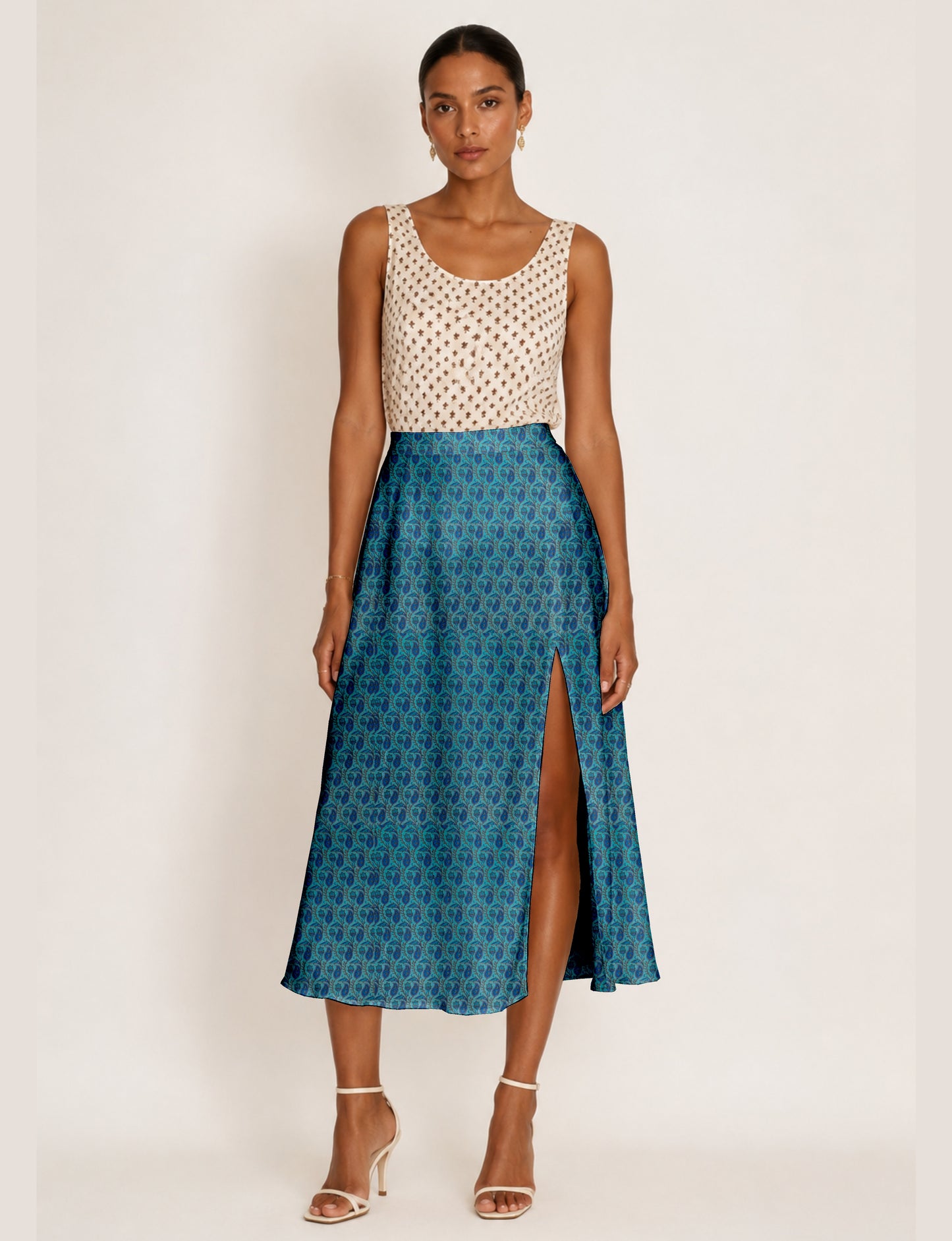 Woman wearing a yellow and black micro patterned A-line skirt with front slit, paired with beige sleeveless top and black