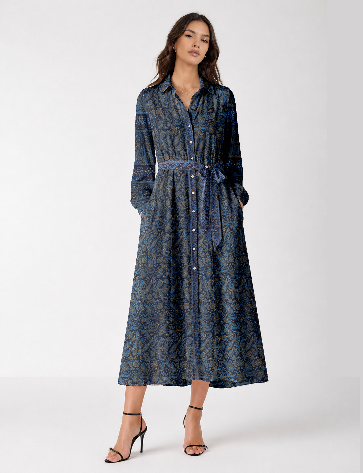 Woman wearing a long blue paisley shirt dress with button front, collar, long sleeves, and a matching fabric belt tied at