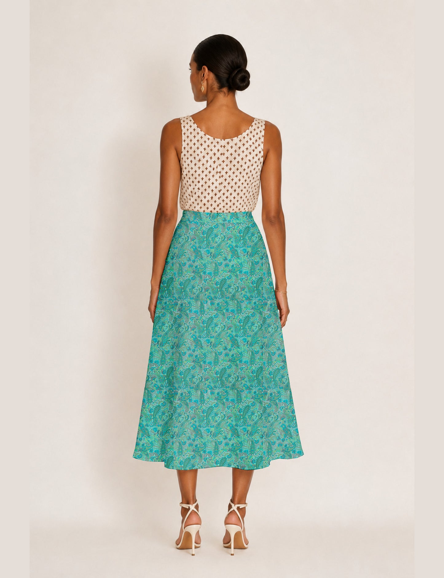 Woman wearing a yellow and black micro patterned A-line skirt with front slit, paired with beige sleeveless top and black