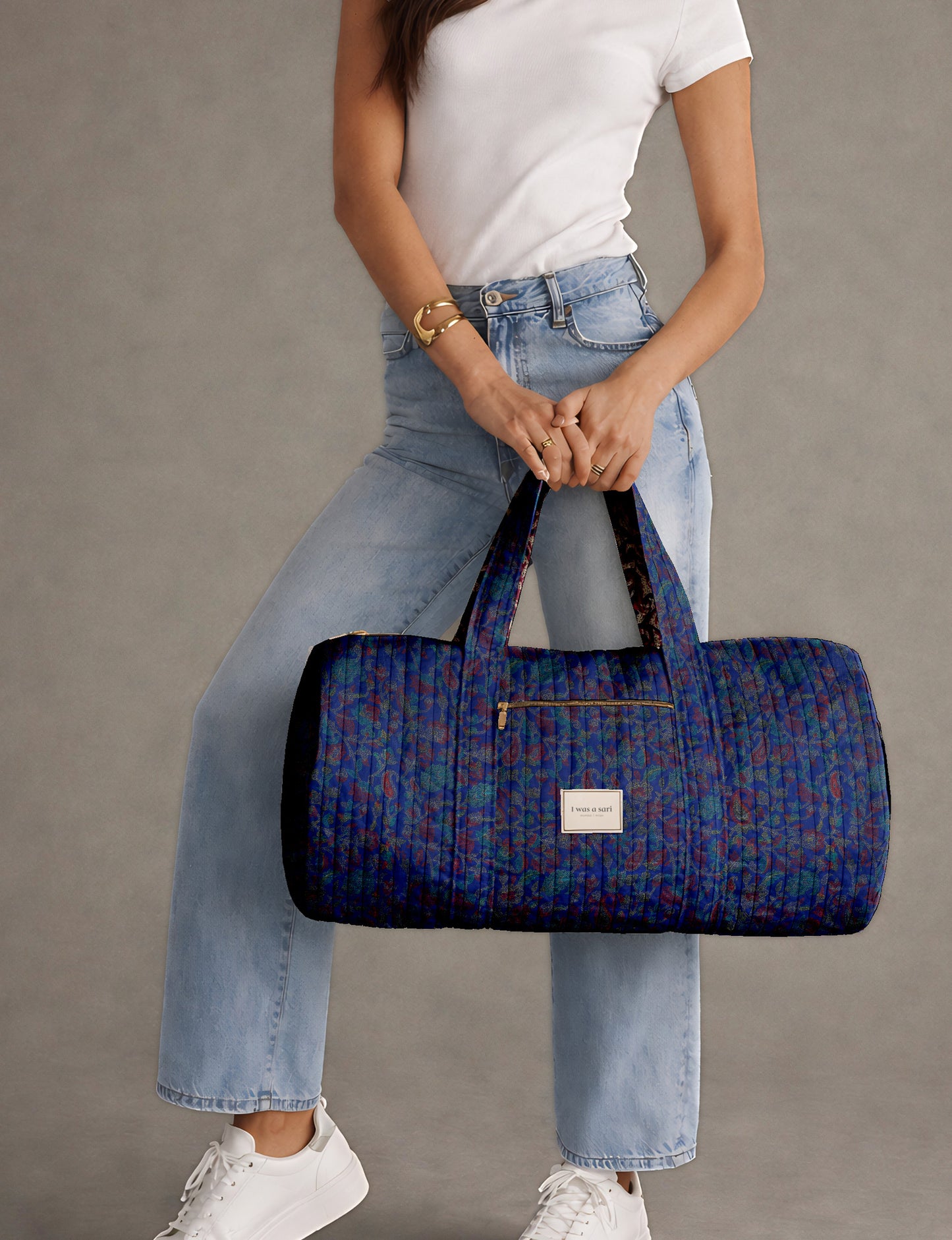Brown paisley quilted bowling bag with front zipper pocket, held by person wearing white shirt and light blue jeans