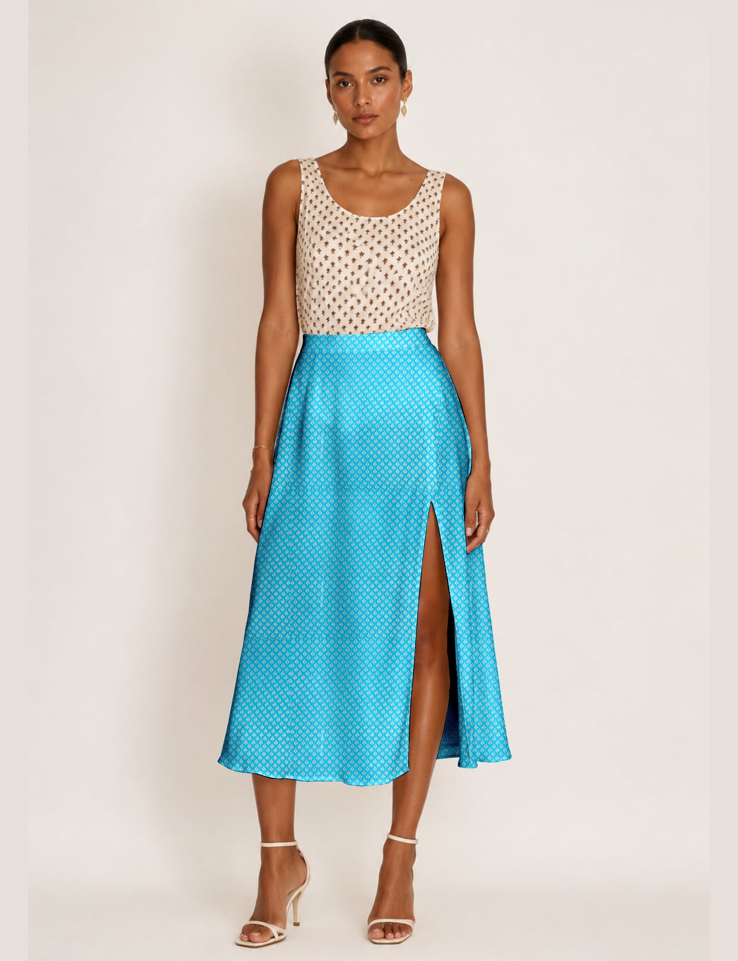Woman wearing a yellow and navy blue A-line skirt with a slit and a sleeveless beige top with brown micro print