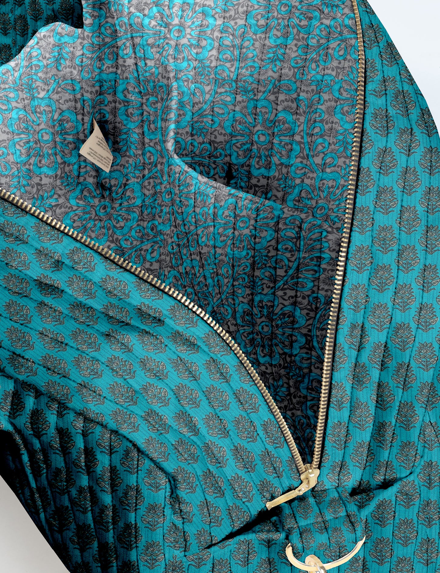 Brown quilted duffle bag with paisley pattern, front zip pocket, dual handles, and label reading "I was a sari"