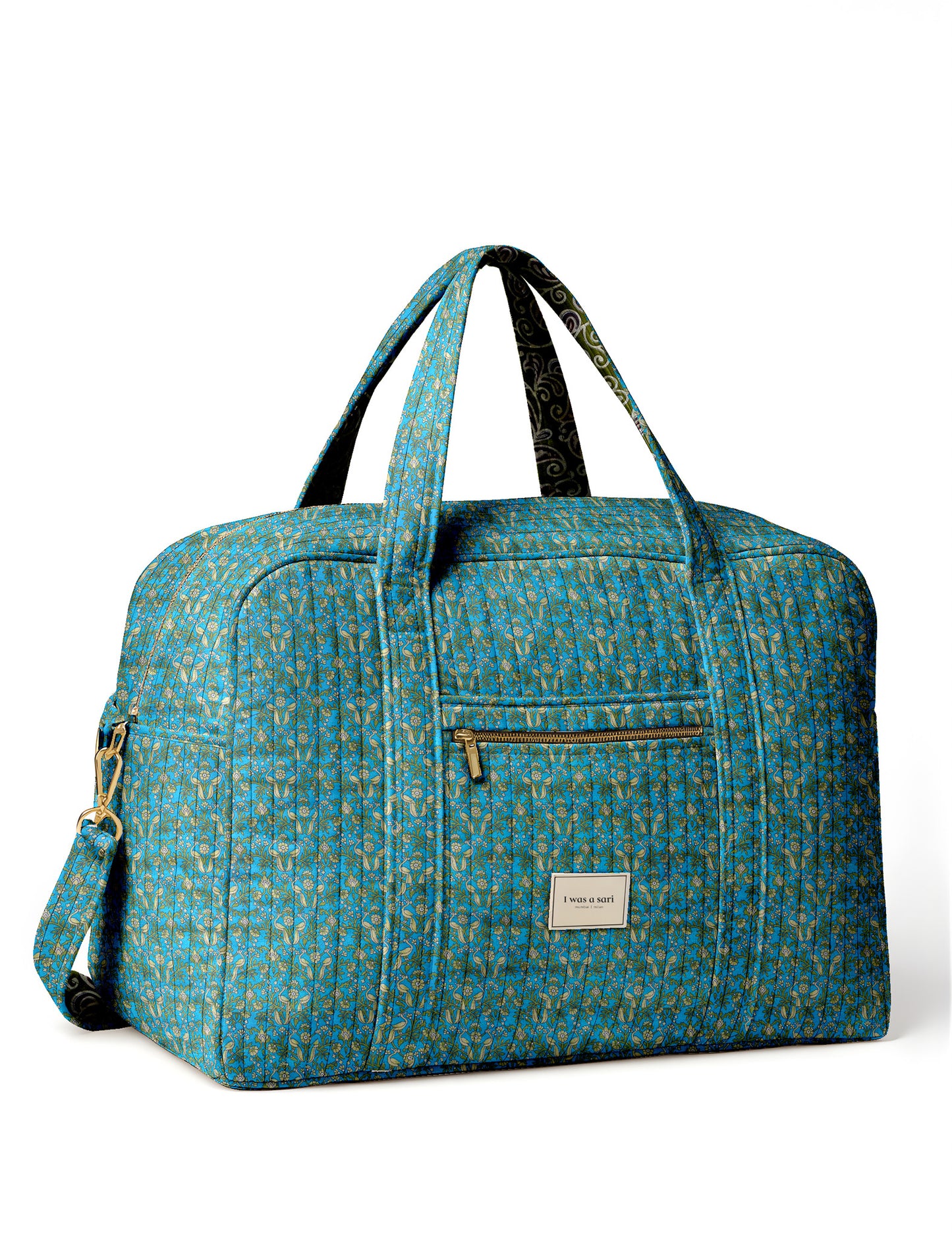 Brown quilted duffle bag with paisley pattern, front zip pocket, dual handles, and label reading "I was a sari"