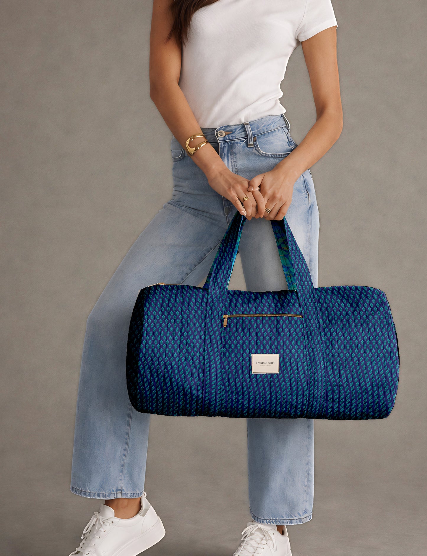 Brown paisley quilted bowling bag with front zipper pocket, held by person wearing white shirt and light blue jeans