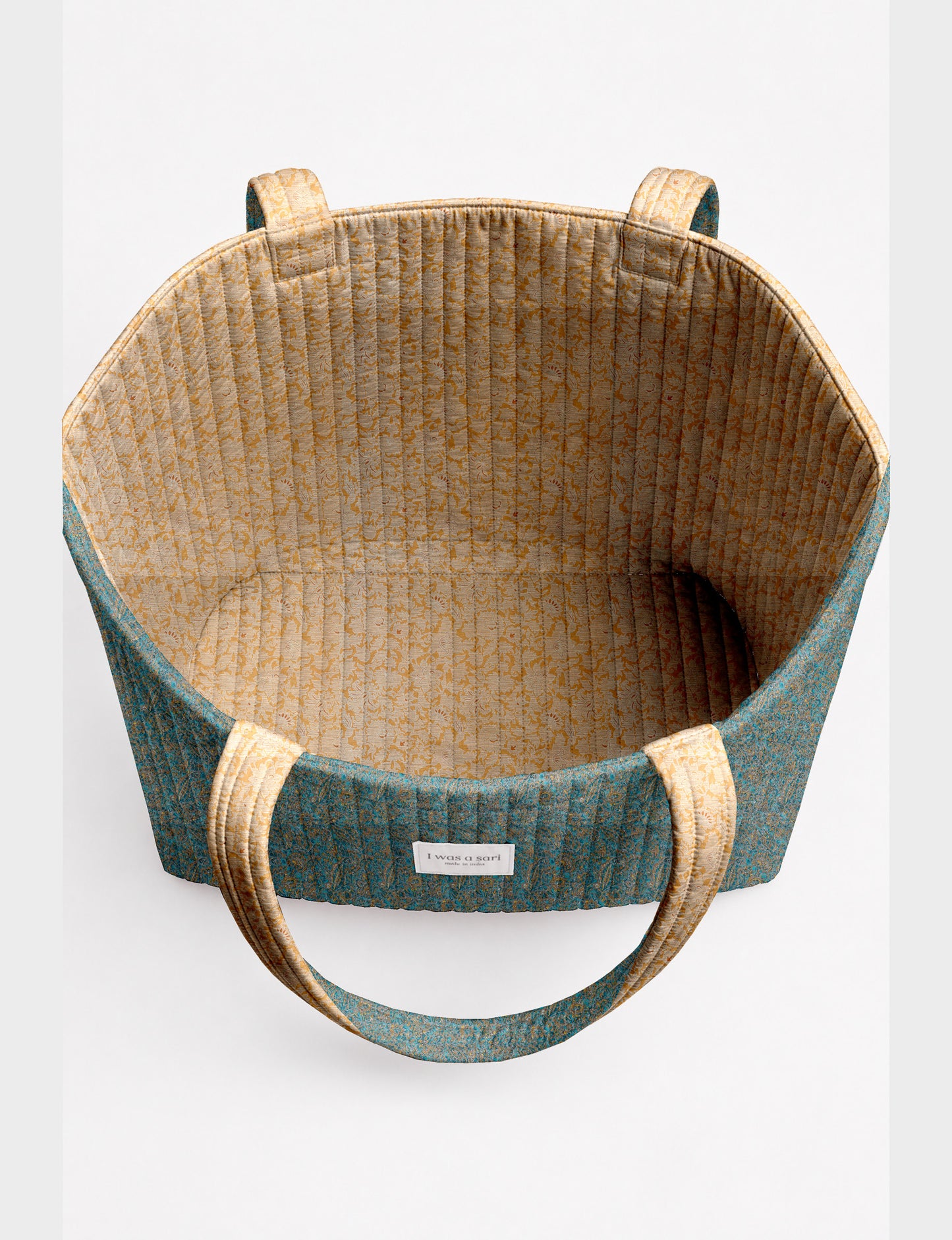Quilted beach bag with yellow tropical exterior and red patterned interior, shown from top view with handles visible