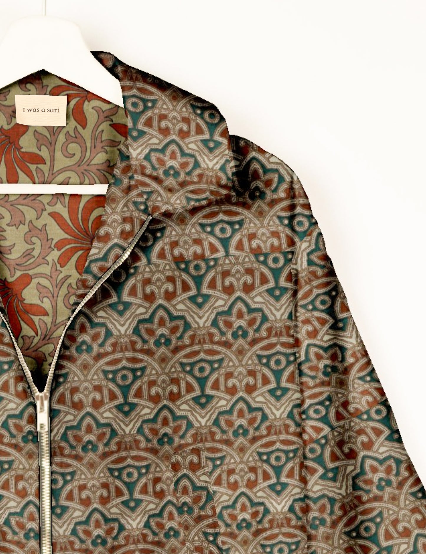 Green bomber jacket with Indian ethnic floral and geometric patterns, front zipper, shown on hanger with "I was a sari"