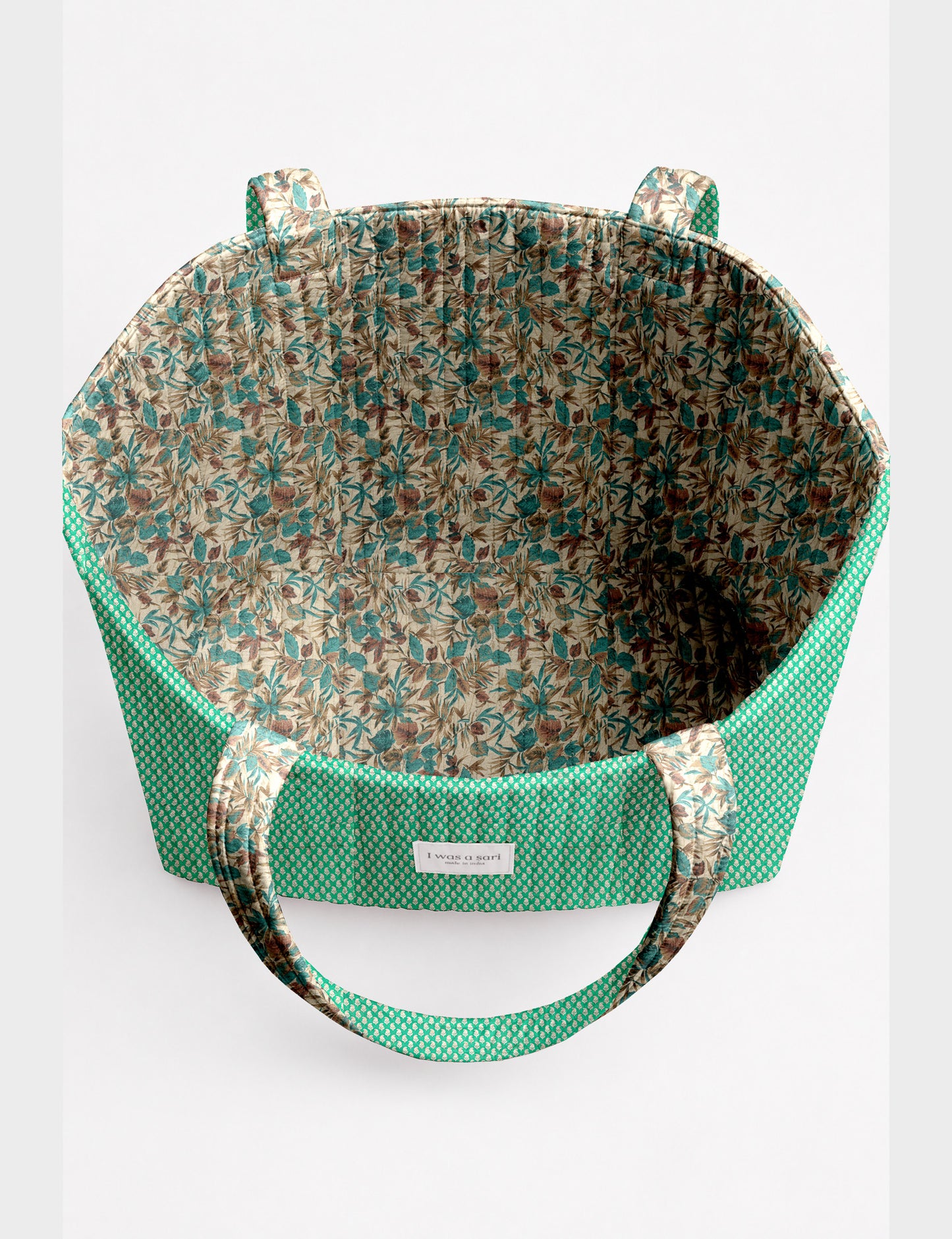 Quilted beach bag with yellow tropical exterior and red patterned interior, shown from top view with handles visible