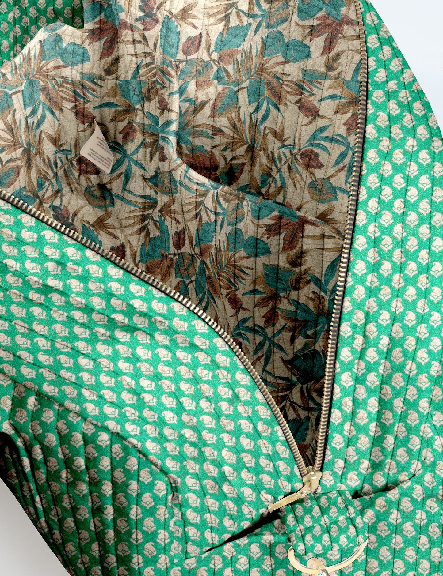 Brown quilted duffle bag with paisley pattern, front zip pocket, dual handles, and label reading "I was a sari"
