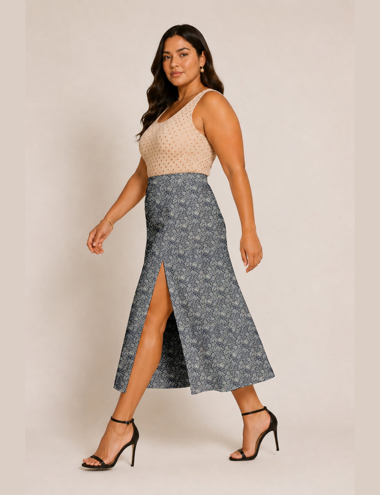 Woman wearing a yellow and black micro patterned A-line skirt with front slit, paired with beige sleeveless top and black