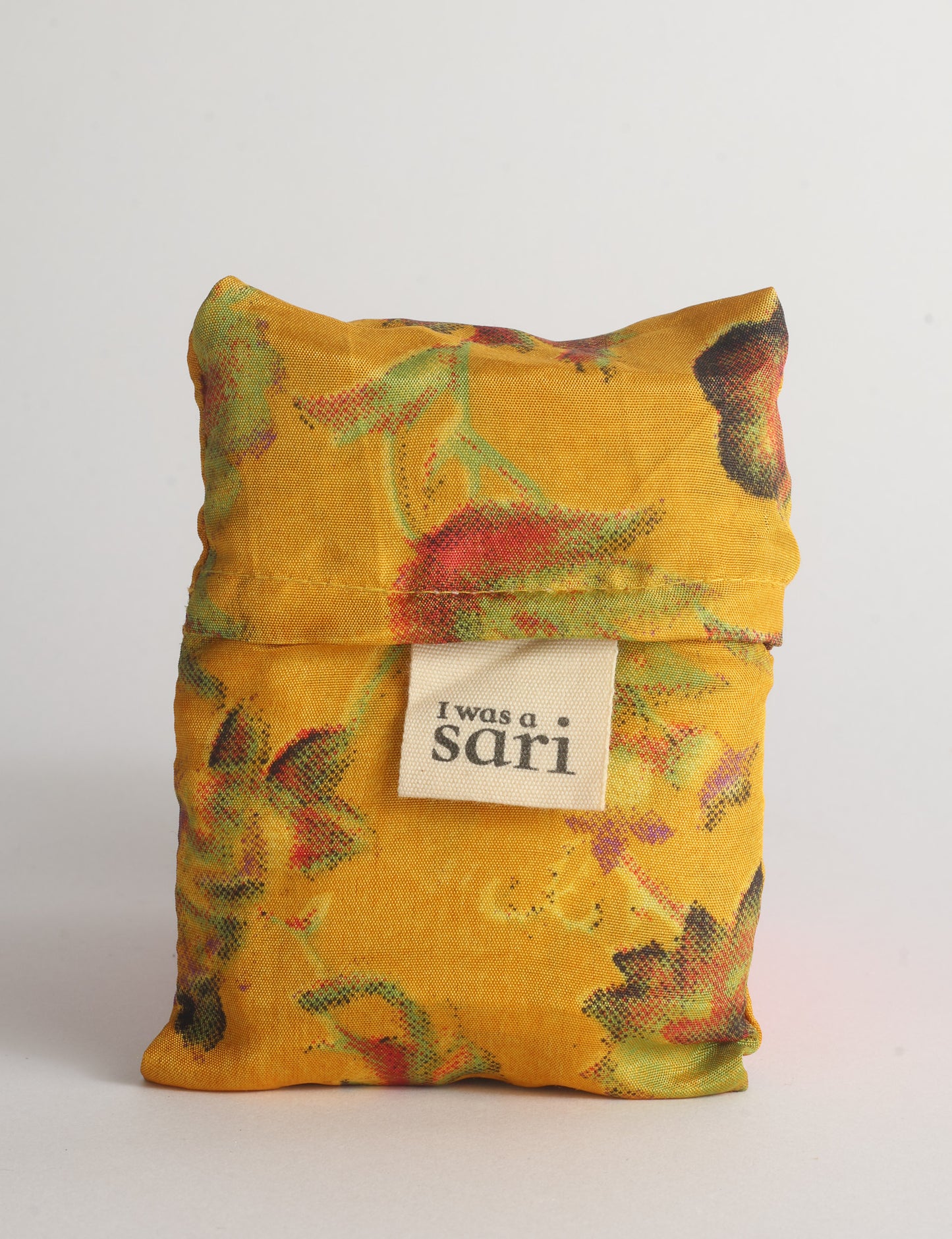 Blue reusable bag with multicolor tropical floral pattern folded with "I was a sari" label visible on front