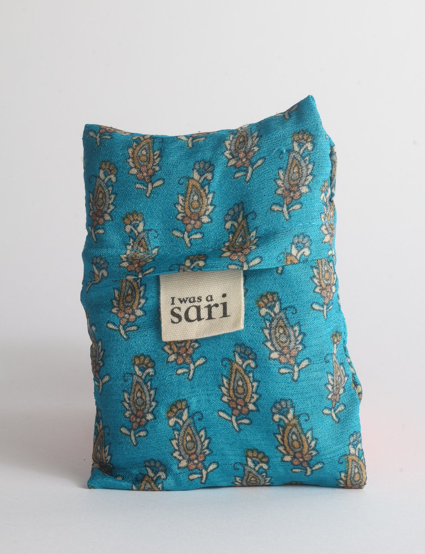 Blue reusable bag with multicolor tropical floral pattern folded with "I was a sari" label visible on front