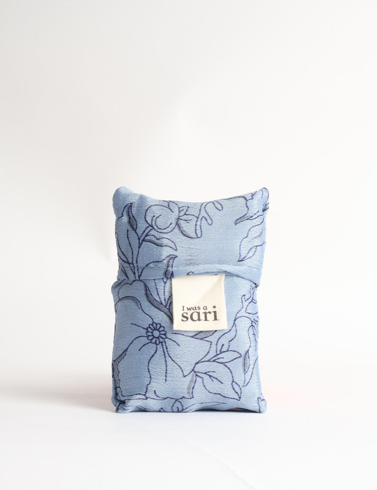 Blue reusable bag with tropical floral pattern in pink, yellow, and green, shown hanging with handles visible
