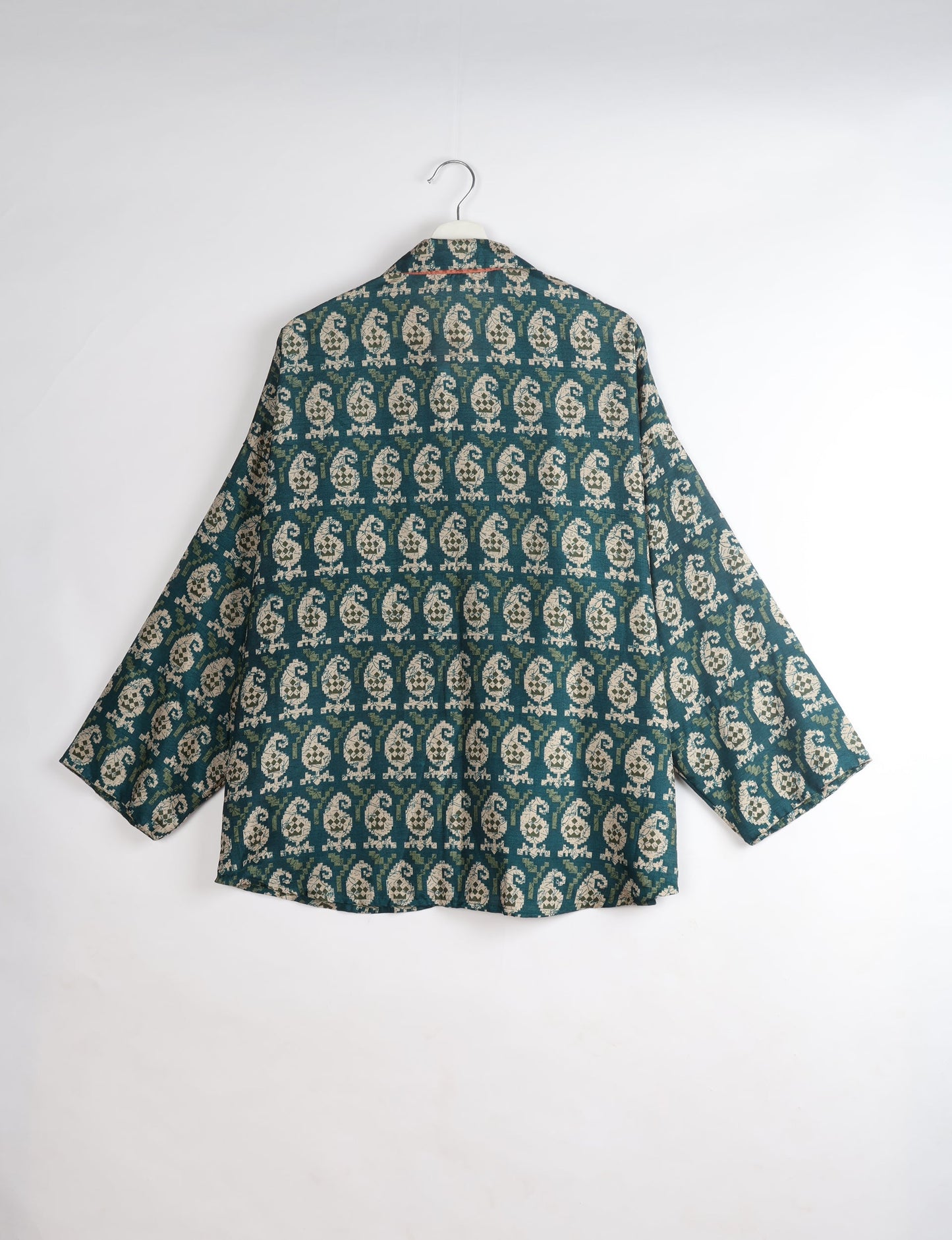 Oversized green shirt with beige paisley pattern, long sleeves, and spread collar, shown from back on hanger