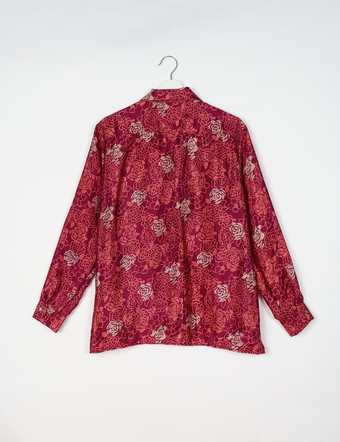 Long-sleeve pink floral resort shirt with buttoned cuffs, shown from back on white hanger against white background