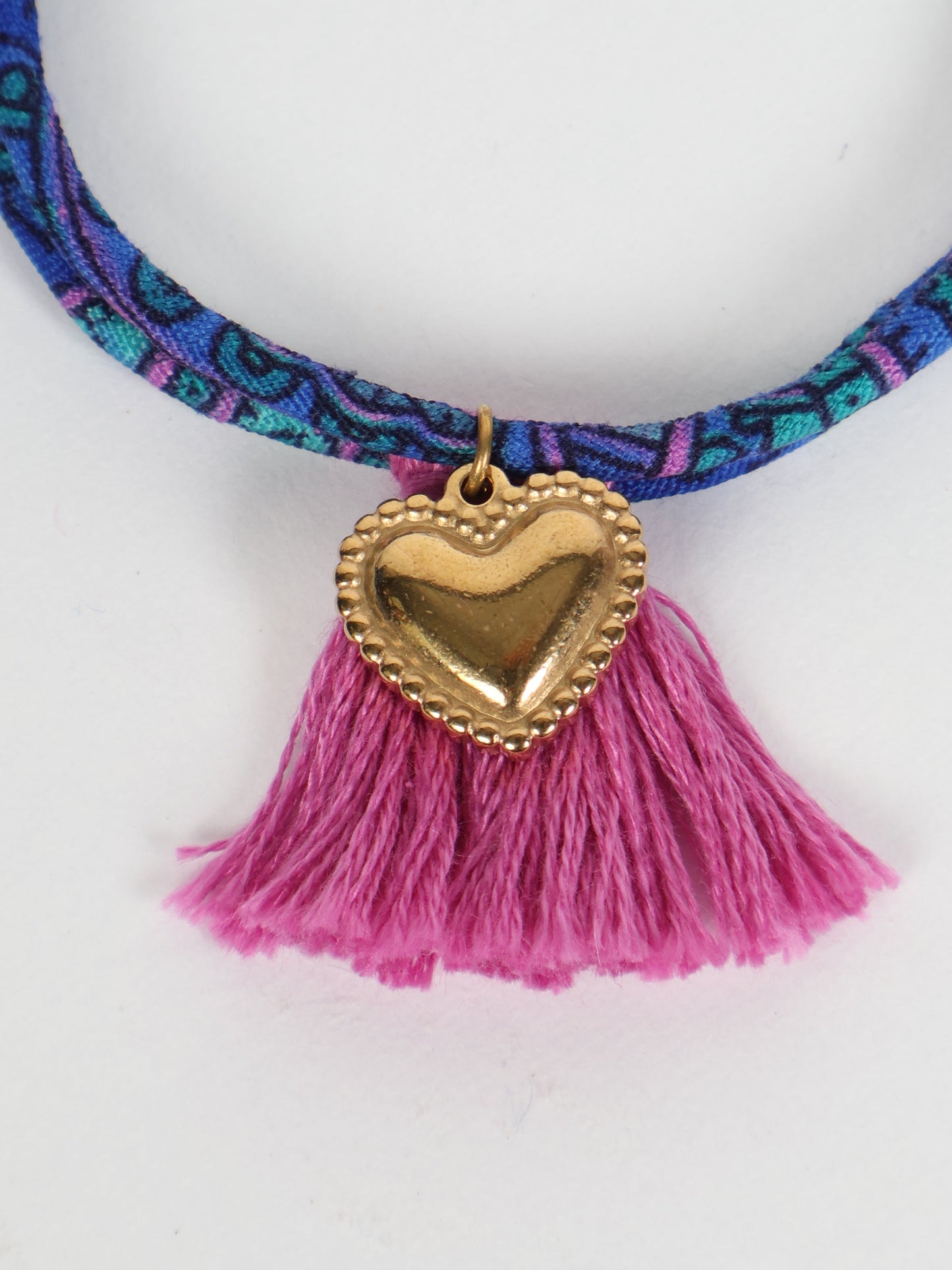 Handmade rope bracelet from recycled sari fabric with gold heart charm and tassels—eco friendly cloth, climate neutral fashion, and upcycled women’s clothing.