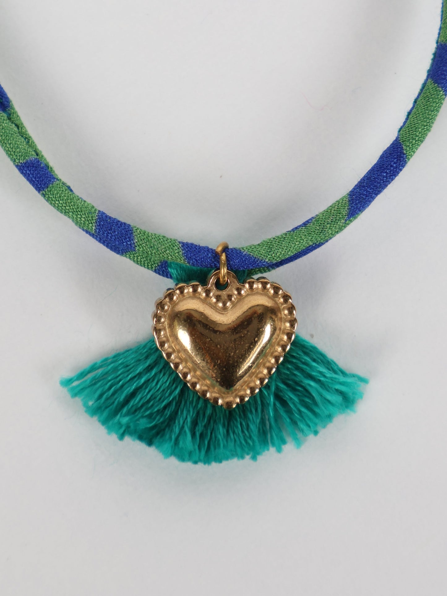 Handmade rope bracelet from recycled sari fabric with gold heart charm and tassels—eco friendly cloth, climate neutral fashion, and upcycled women’s clothing.