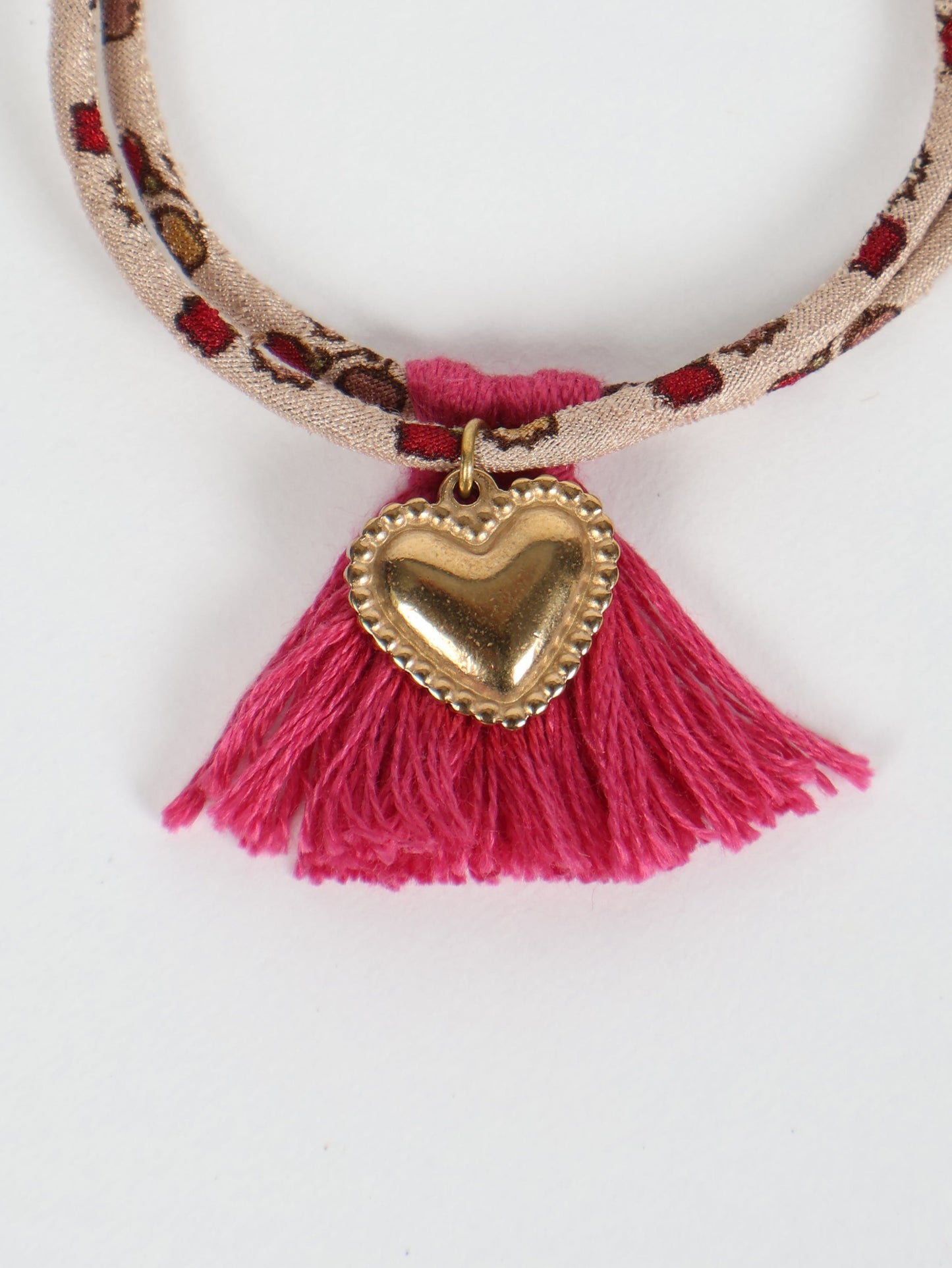Handmade rope bracelet from recycled sari fabric with gold heart charm and tassels—eco friendly cloth, climate neutral fashion, and upcycled women’s clothing.