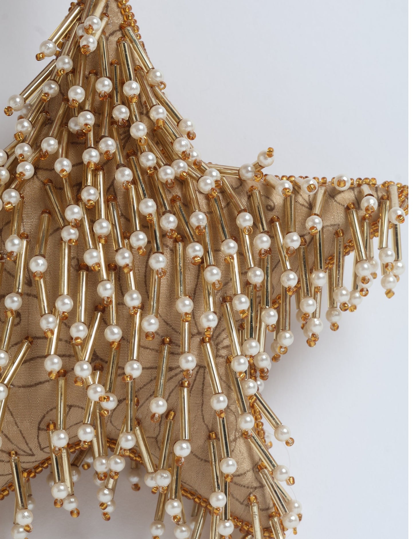 Gold star ornament with beige floral fabric base decorated with gold tubes and white pearl beads, close-up view