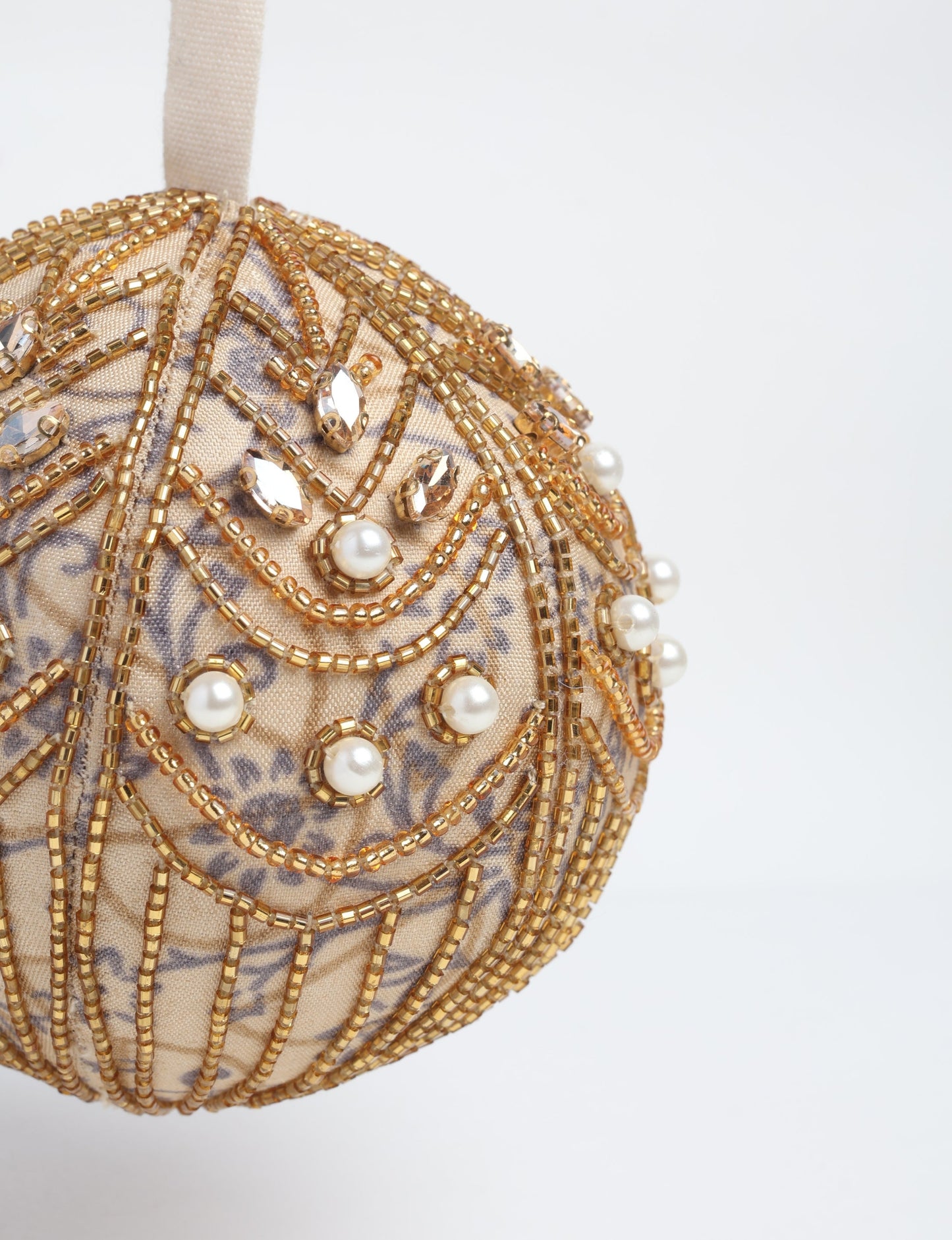 Gold colored ball ornament handcrafted from recycled sari products and repurposed clothing, featuring silver hand embroidery, pearls, sequins, and beads. Made through circular fashion and sustainable women’s clothing processes, this piece represents eco friendly fashion, carbon neutral clothing, and environmentally friendly clothing inspired by conscious clothing principles.