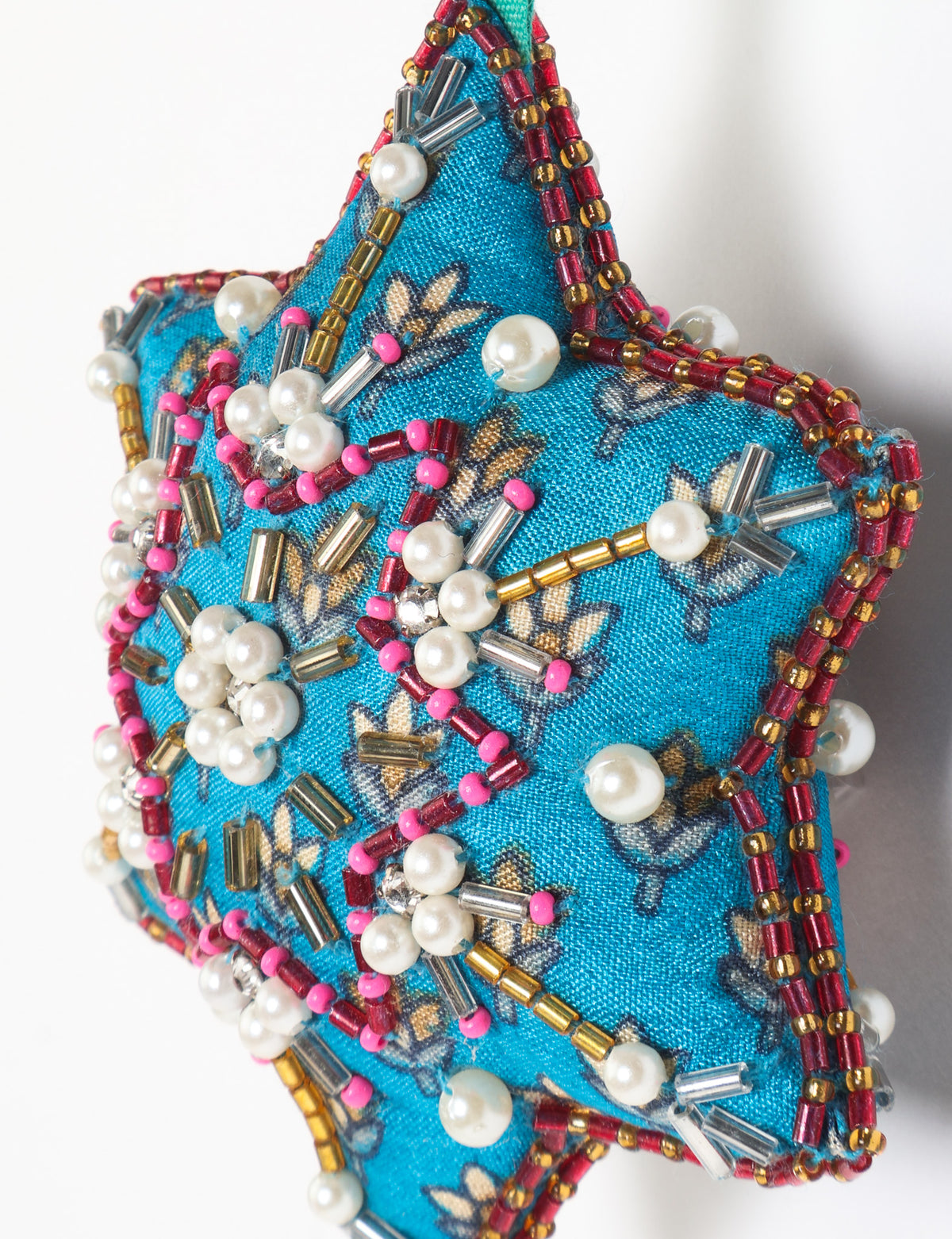 Teal fabric star-shaped snowflake ornament with bead and pearl embellishments, hanging by a teal fabric loop