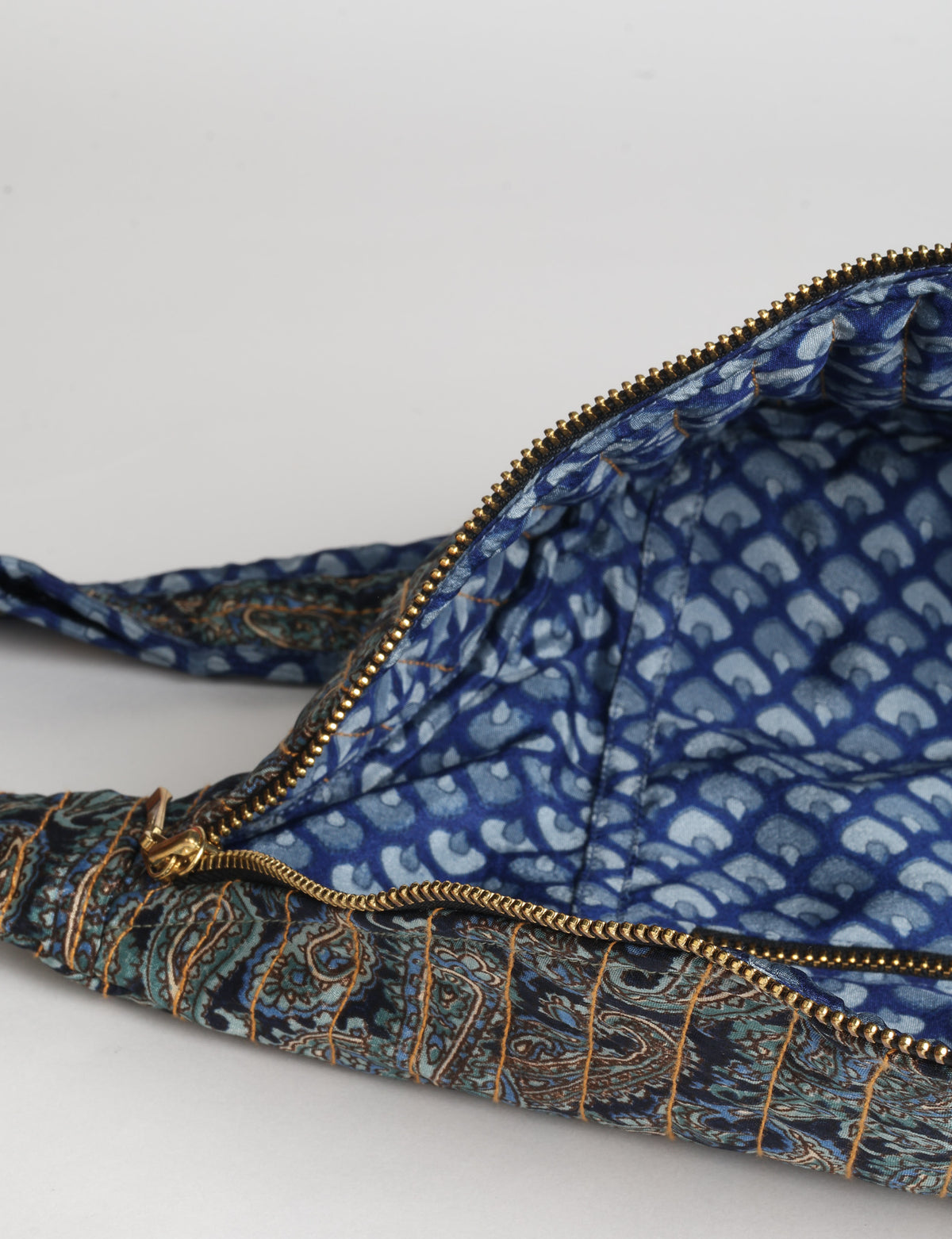 Quilted large shoulder bag with a curved silhouette, adjustable strap and zip-top closure.