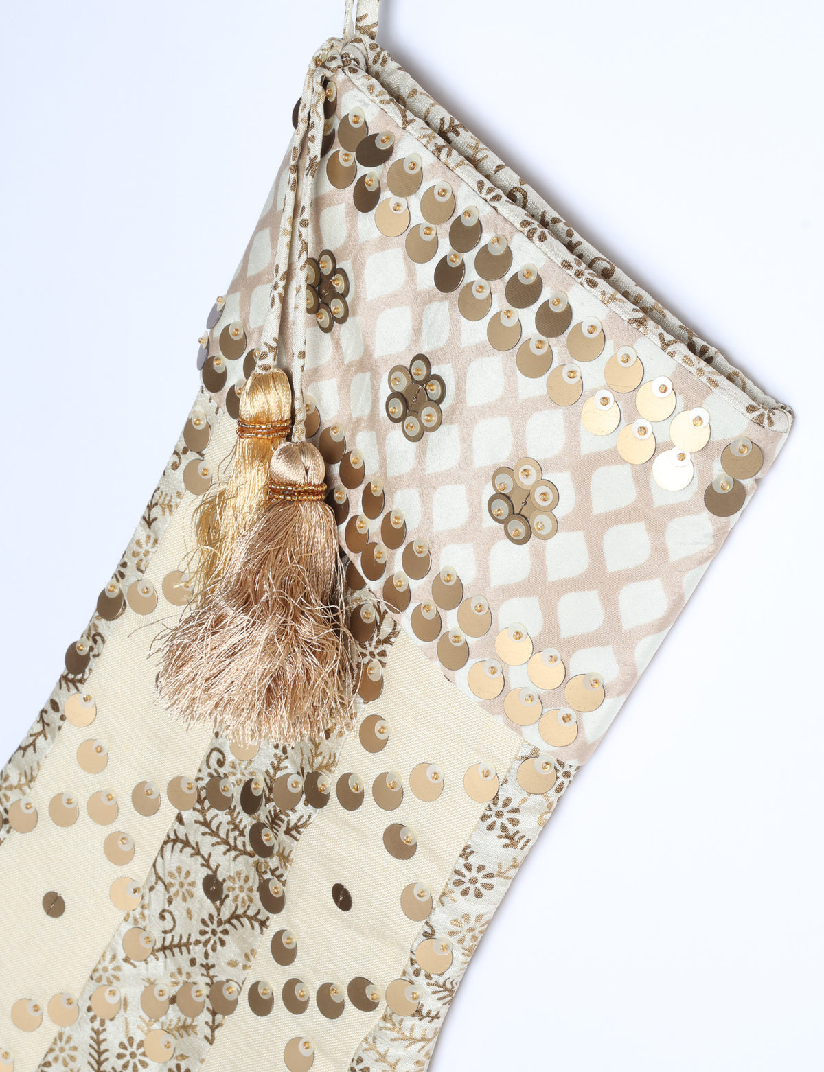 Christmas stocking with beige and brown floral and stripe pattern, gold sequins, and two beige tassels on hanging loop