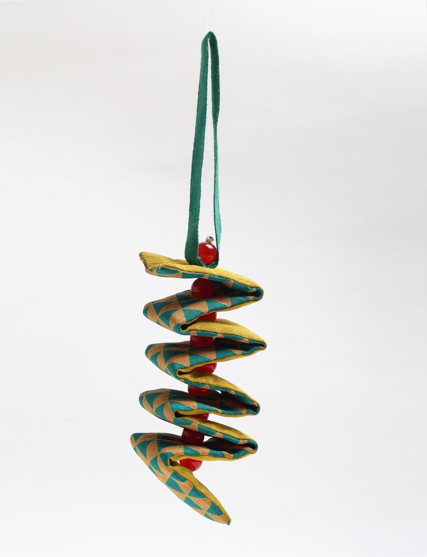 Hanging fabric ornament with green and yellow geometric pattern and red beads threaded through the center