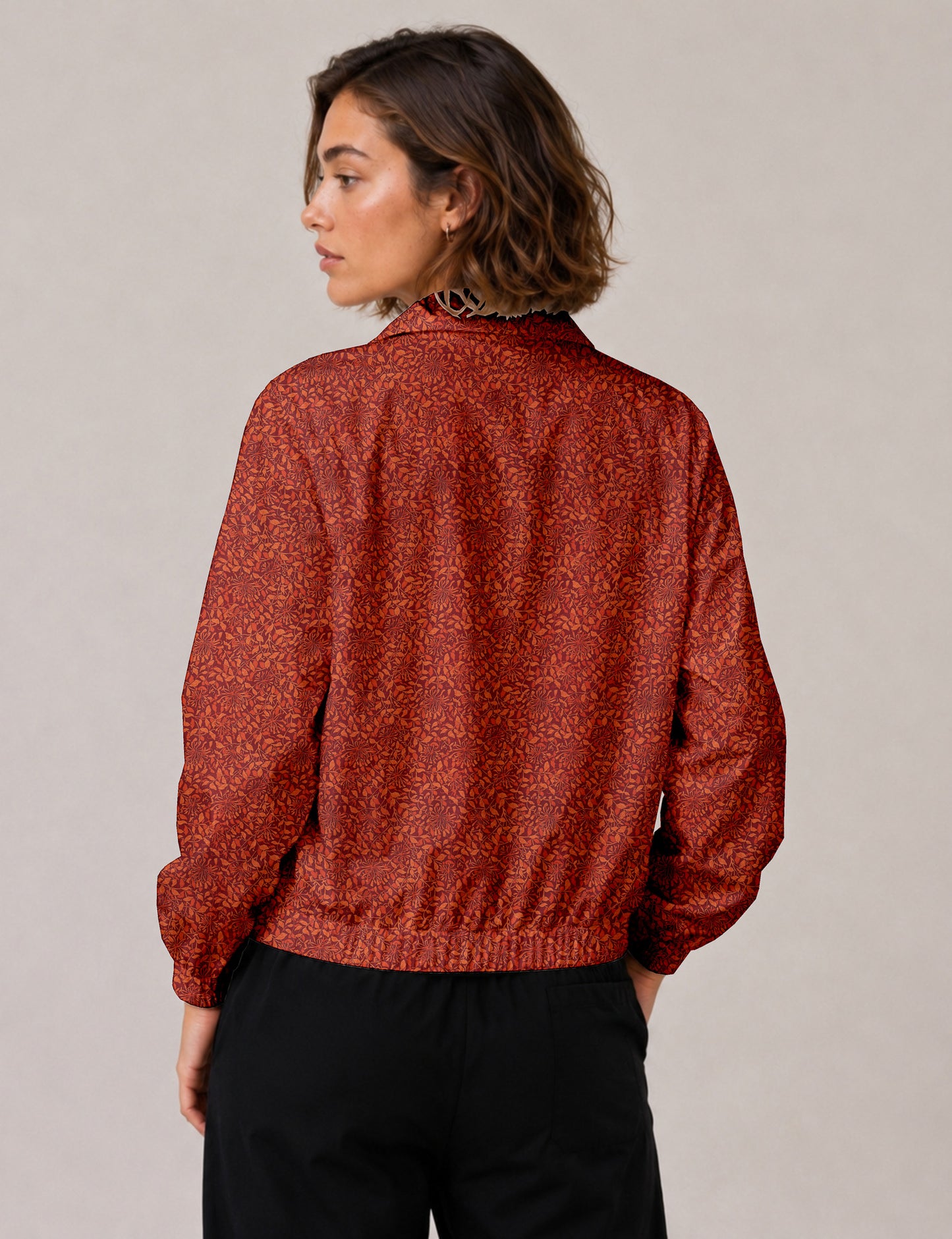 Woman wearing a yellow floral bomber jacket with front zipper, elastic cuffs, and side pockets, shown from front view