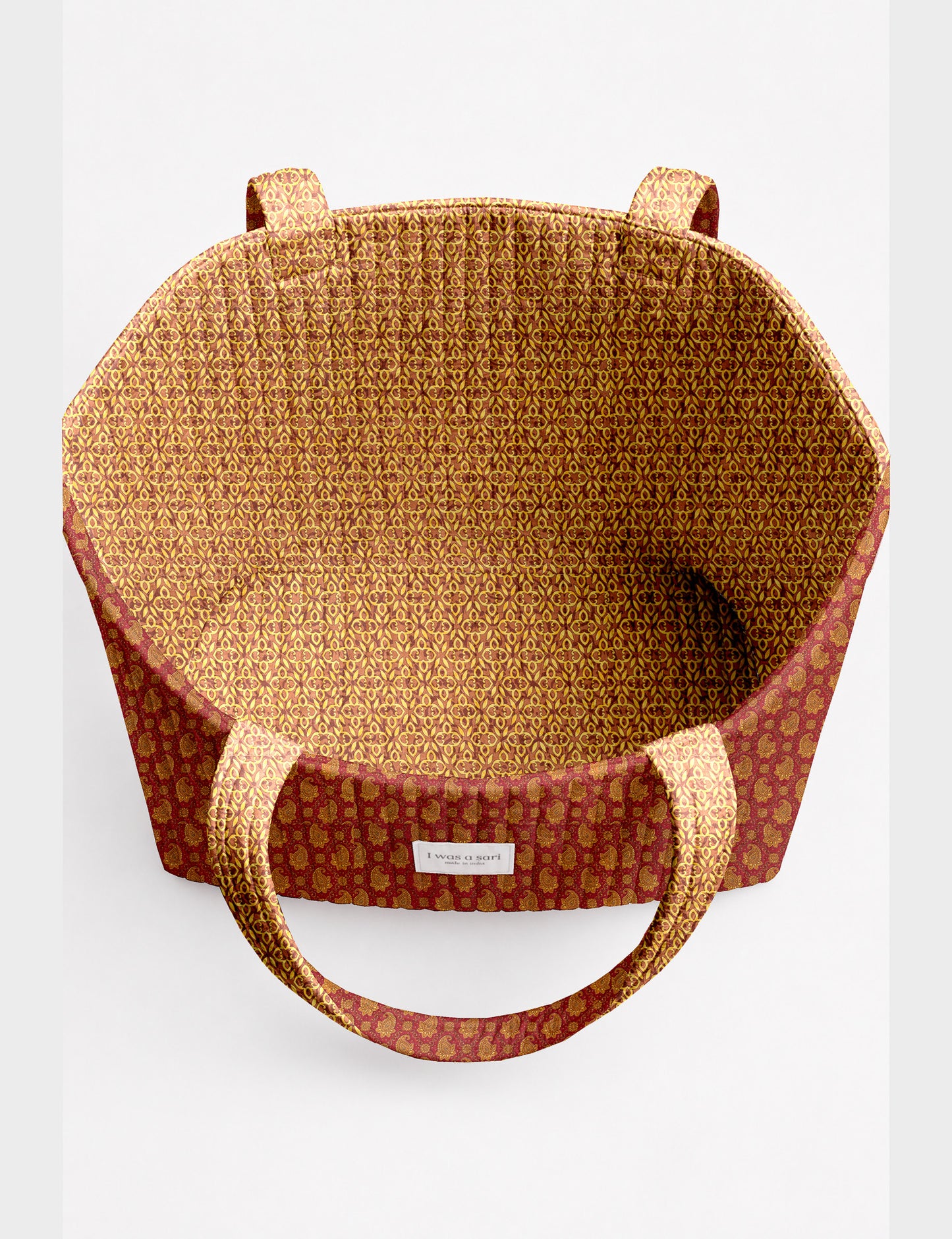 Quilted beach bag with yellow tropical exterior and red patterned interior, shown from top view with handles visible