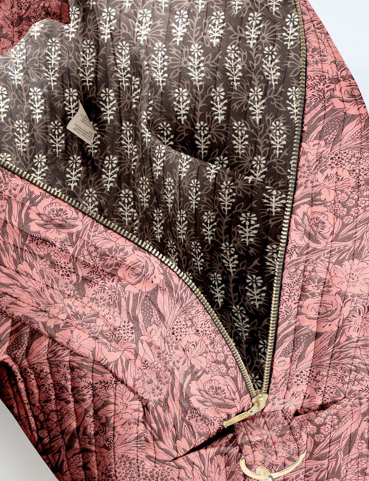Brown quilted duffle bag with paisley pattern, front zip pocket, dual handles, and label reading "I was a sari"