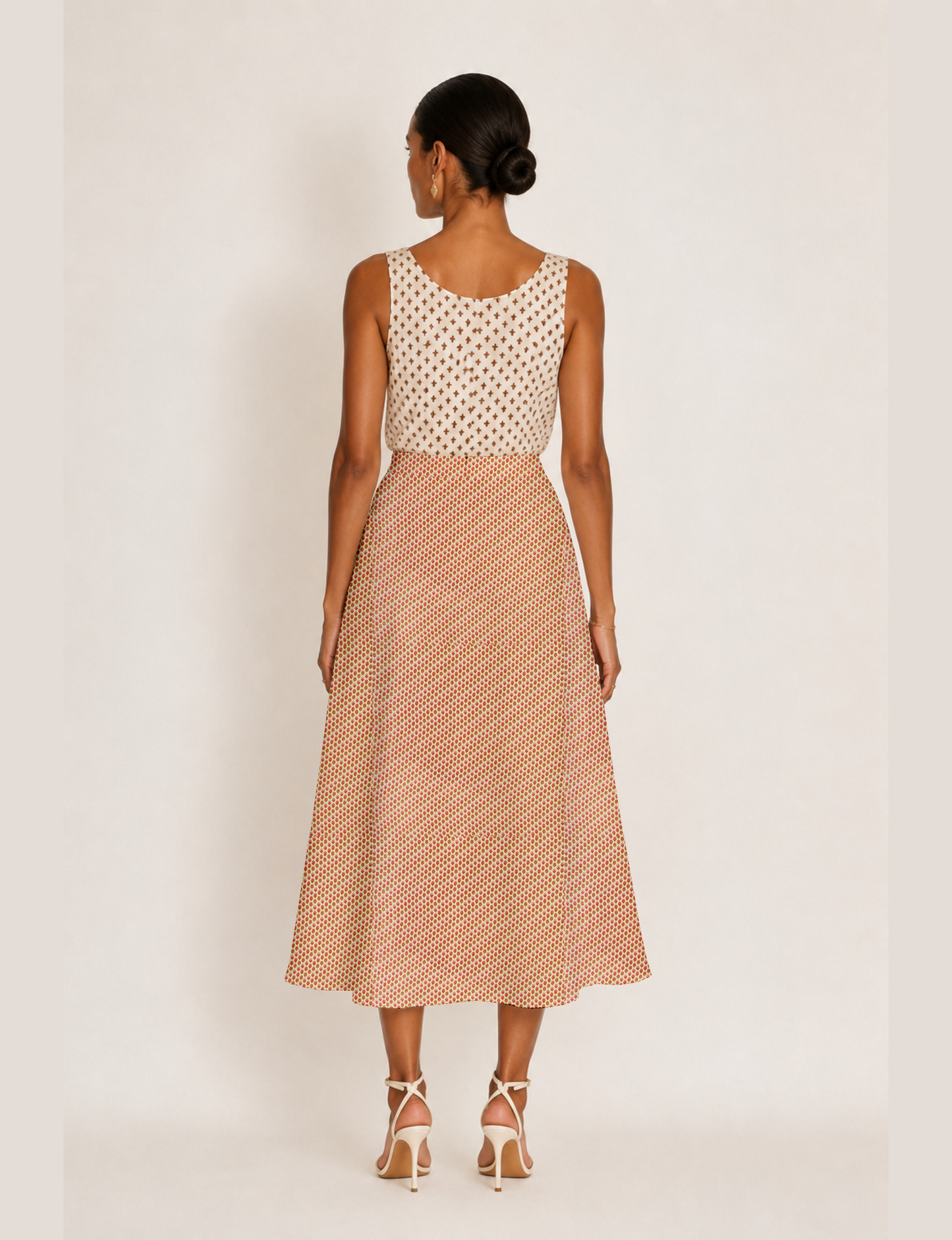 Woman wearing a yellow and black micro patterned A-line skirt with front slit, paired with beige sleeveless top and black