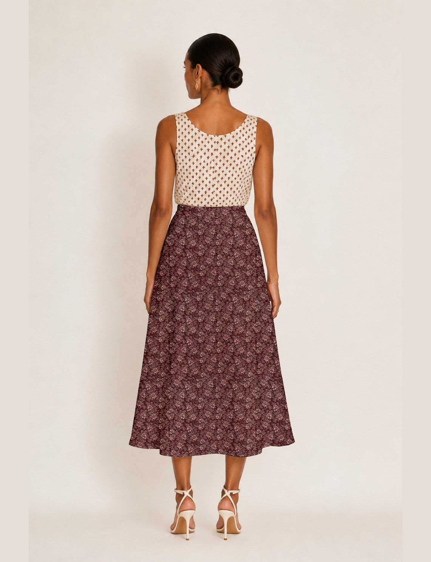 Woman wearing a yellow and black micro patterned A-line skirt with front slit, paired with beige sleeveless top and black