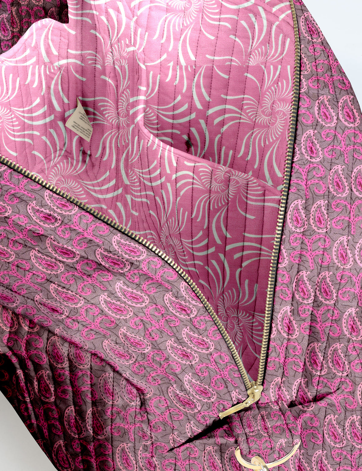 Brown quilted duffle bag with paisley pattern, front zip pocket, dual handles, and label reading "I was a sari"